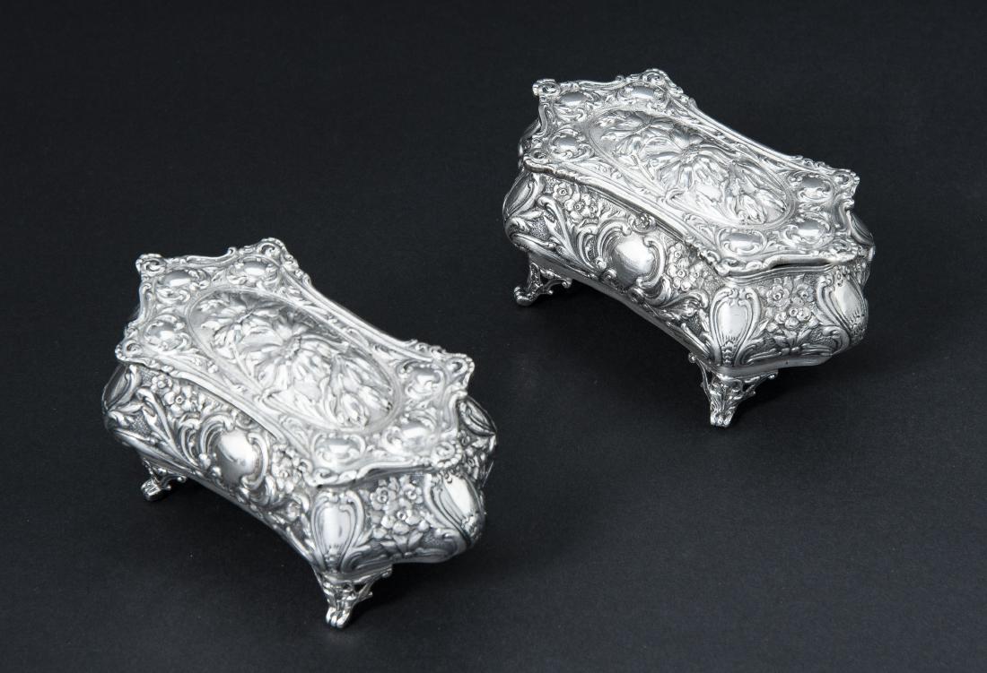 Pair German Sterling Jewelry Caskets: DESCRIPTION: Pair of German sterling repousse jewelry caskets with red fabric interiors. MEASUREMENTS: Each 4-1/2" wide x 2-1/2" deep x 2-1/4" high. 12.6 troy ounces total. CONDITION: Light surface sc