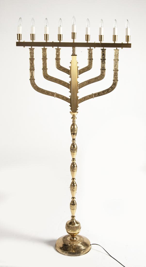 Large Brass Synagogue Chanukah Menorah: DESCRIPTION: Large brass synagogue Chanukah menorah. Gold finish. Six arms decorated with flowers and ornamental imagery. Wired for electricity. Marked on bottom "Solid Brass". MEASUREMENTS: 36" x 12"