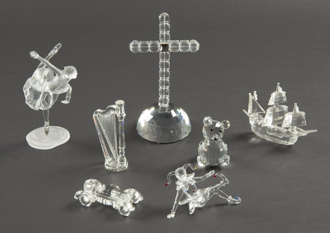7 Swarovski Assorted Pcs: DESCRIPTION: Seven Swarovski assorted pieces. Includes cross of light, ship, ballerina, jester, teddy bear, harp, and car. MEASURMENTS: Ranges from 1" to 7-1/2" high. CONDITION: Excellent. Light shelf