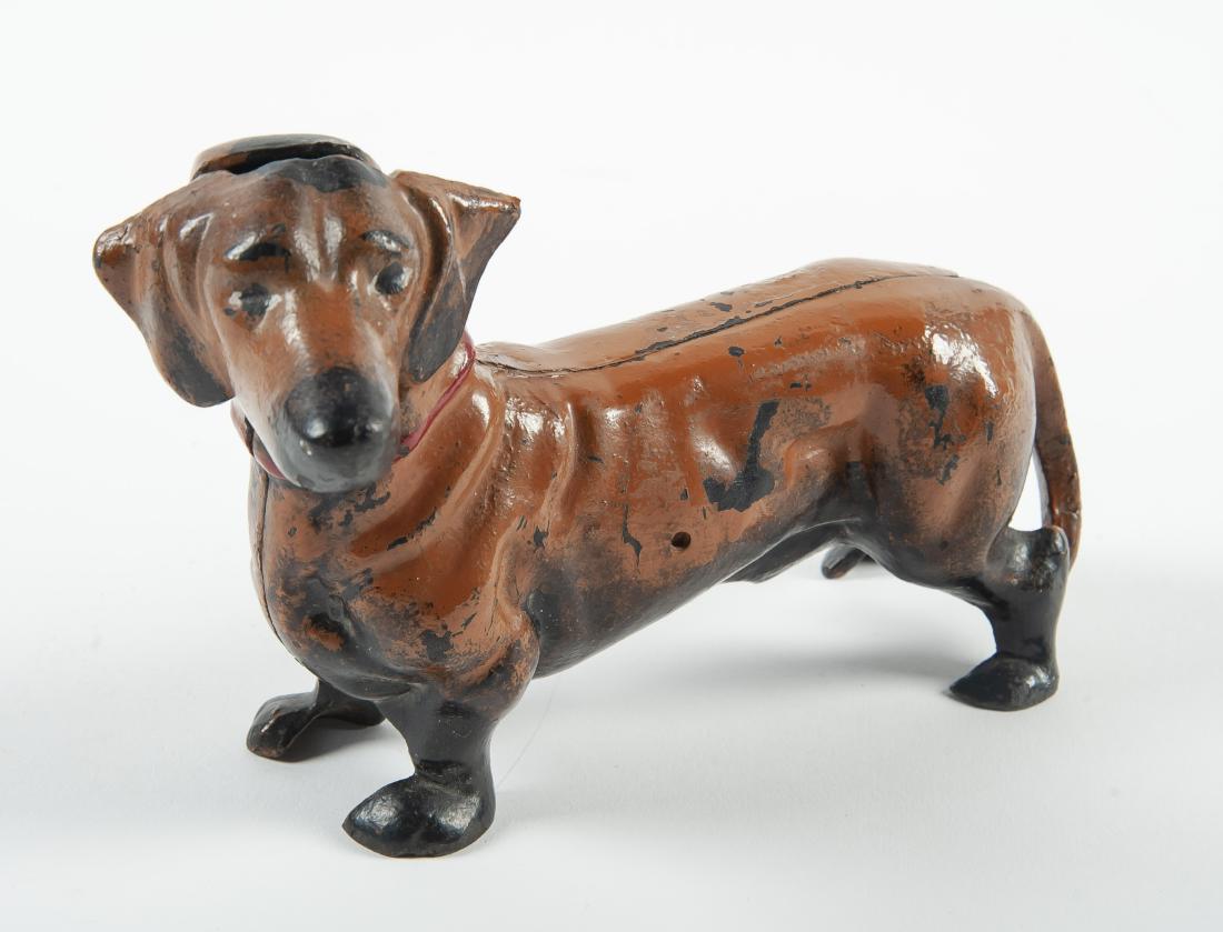 Hubley Cast Iron Dachshund Doorstop or Bank: DESCRIPTION: Hubley cast iron dachshund doorstop. With slot on top of head for coins to use as piggy bank. Two piece construction. Tan paint with red collar. MEASUREMENTS: 8" x 3-1/2" x 5". CONDITION: