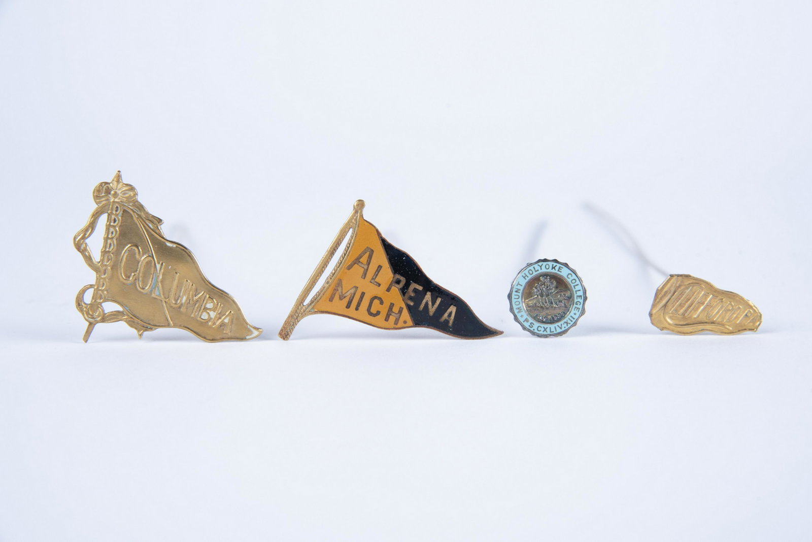 4 Vintage College Hat Pins: DESCRIPTION: Four vintage college hat pins including Alpena Michigan, Columbia, Mount Holyoke, and Clifford PA. MEASUREMENTS: Longest 10". CONDITION: Light wear. Columbia pin with some marks. and bend