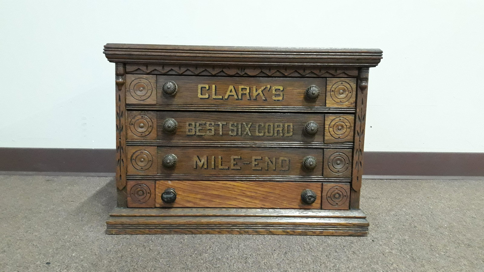 Clark's Spool Cabinet: Four drawers with brass knobs. With gold lettering to front and logo to back. 16" high. Split to top.