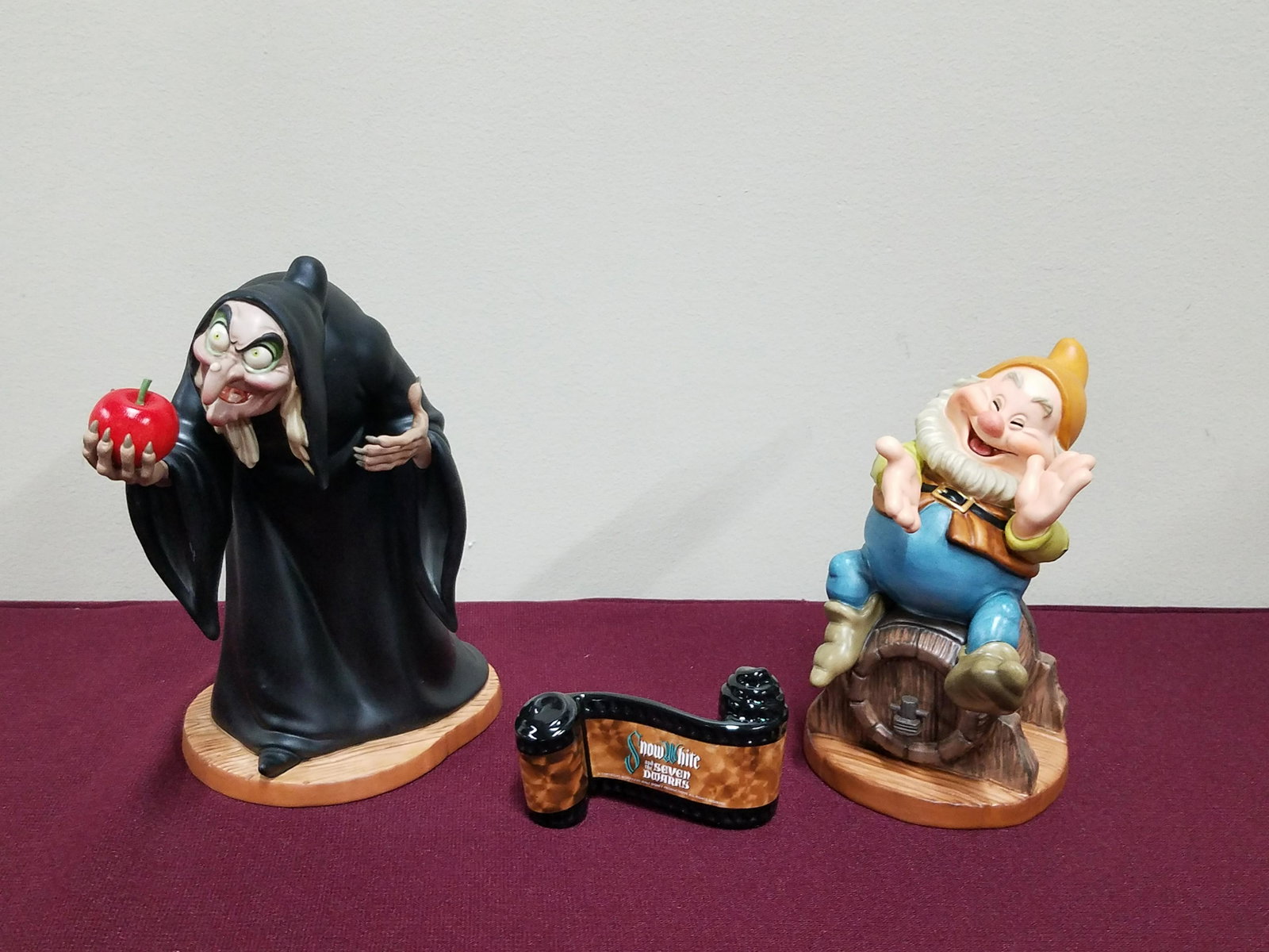 2 Snow White Figures and 1 Film Strip Plaque: Includes "Take the apple, dearie". 7" high. "Happy". 5-1/2" high. Plaque 1-3/4" high. All with original boxes.