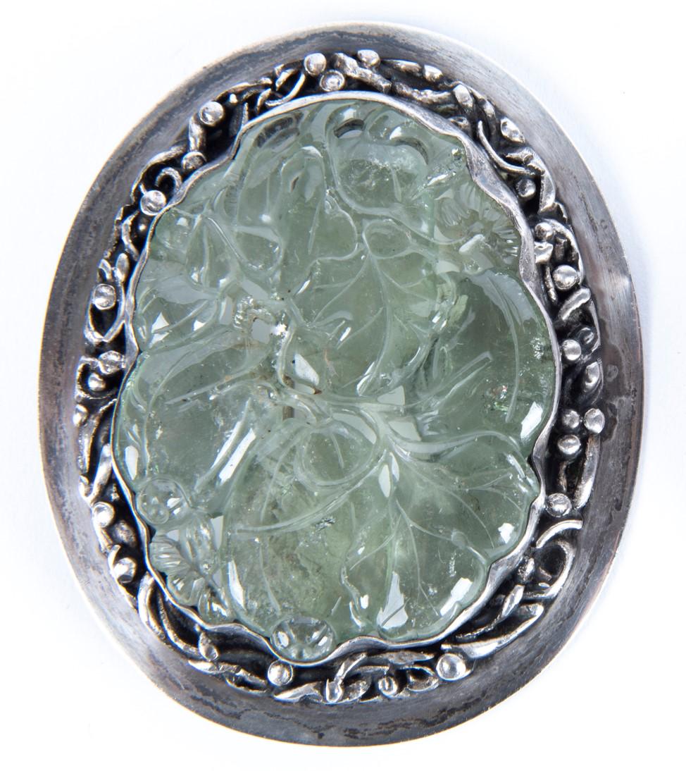 Silver and Icy Jade Brooch: DESCRIPTION: Silver and icy jade brooch with carved foliage design in traslucent jade. MEASUREMENTS: 2-1/2" x 3". CONDITION: Light wear to silver.
