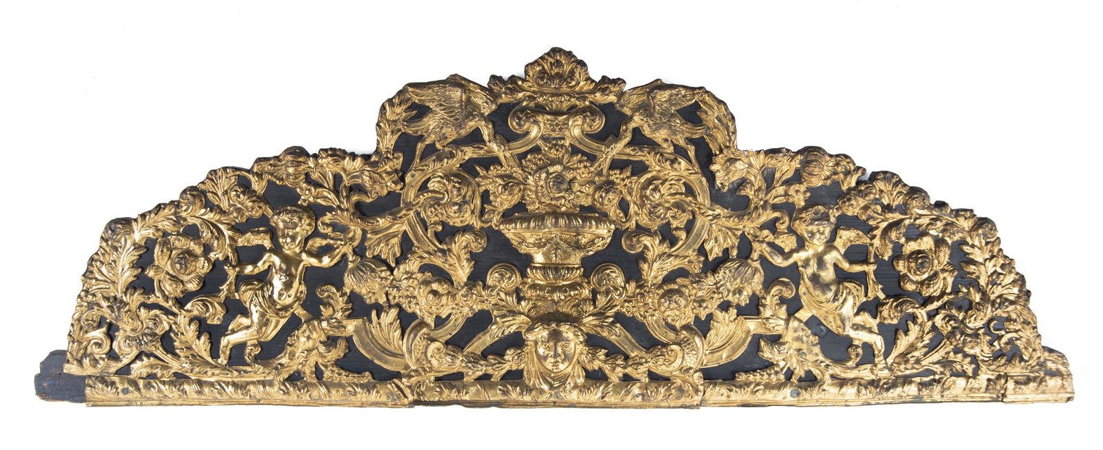 Gilt Decorated Wood Plaque: DESCRIPTION: Gilt decorated wood plaque or cornice. Gold painted tin overlay with cherubs, swag, and floral decoration on black painted wood. Early 20th century. MEASUREMENTS: 44" wide x 1" deep x 15-