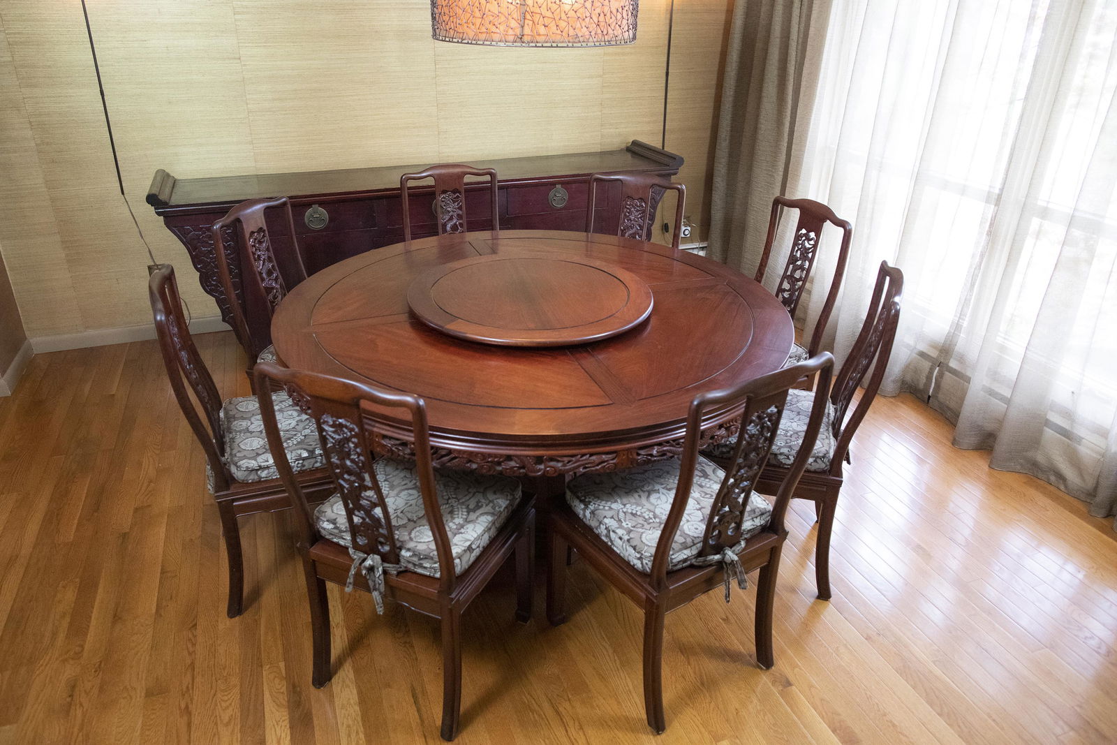 Asian Rosewood Carved Dining Table with 8 Chairs: DESCRIPTION: Asian rosewood carved dining table with eight chairs. Round table with openwork carved skirt with dragon motif on hexagonal base and carved dragon plaques. Table features lazy susan on to