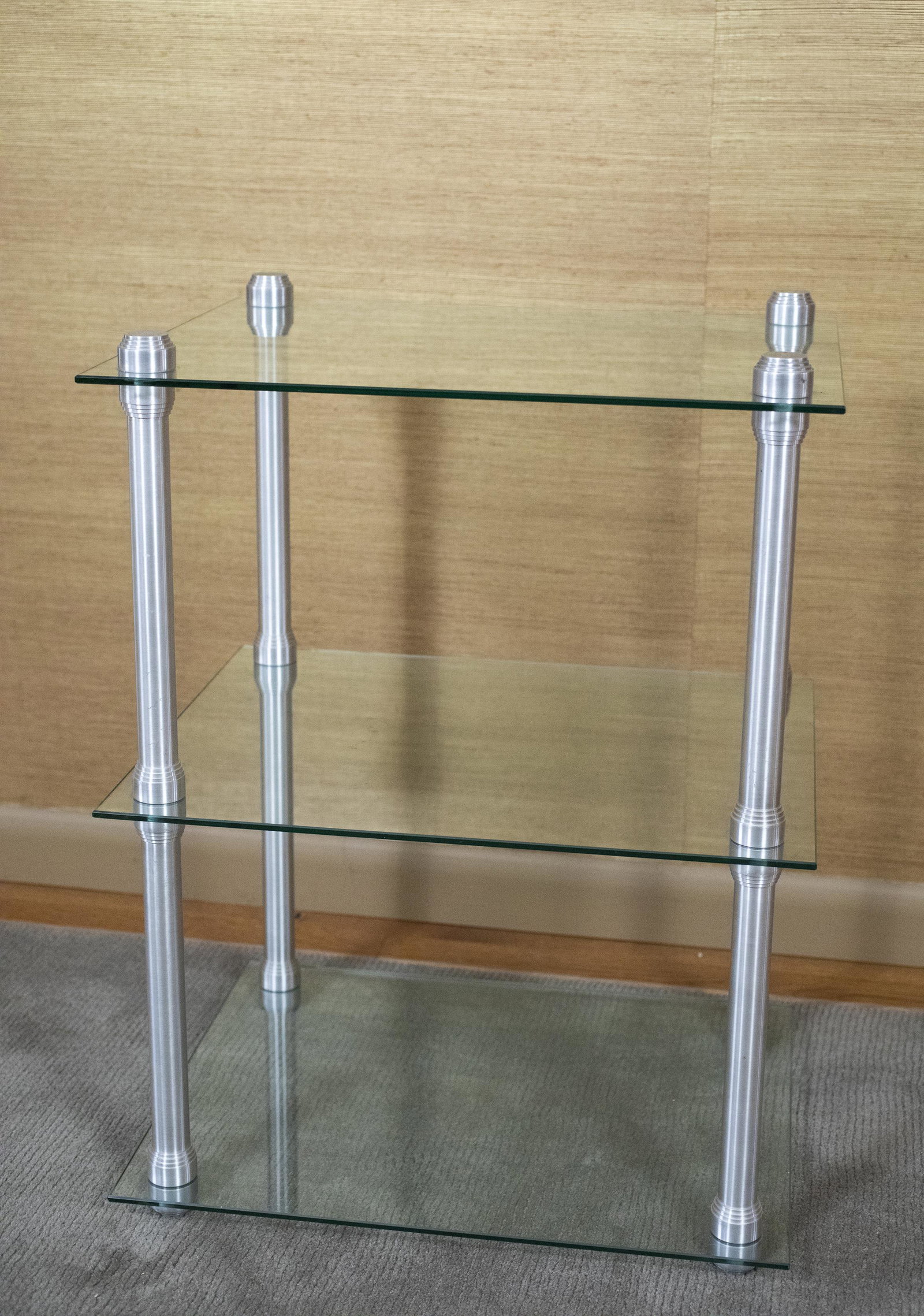 2 Tier Glass & Aluminum Side Table: DESCRIPTION: Square two tiered glass and aluminum side table. MEASUREMENTS: 20" wide x 16" deep x 26-1/2" high. CONDITION: No defects noted.