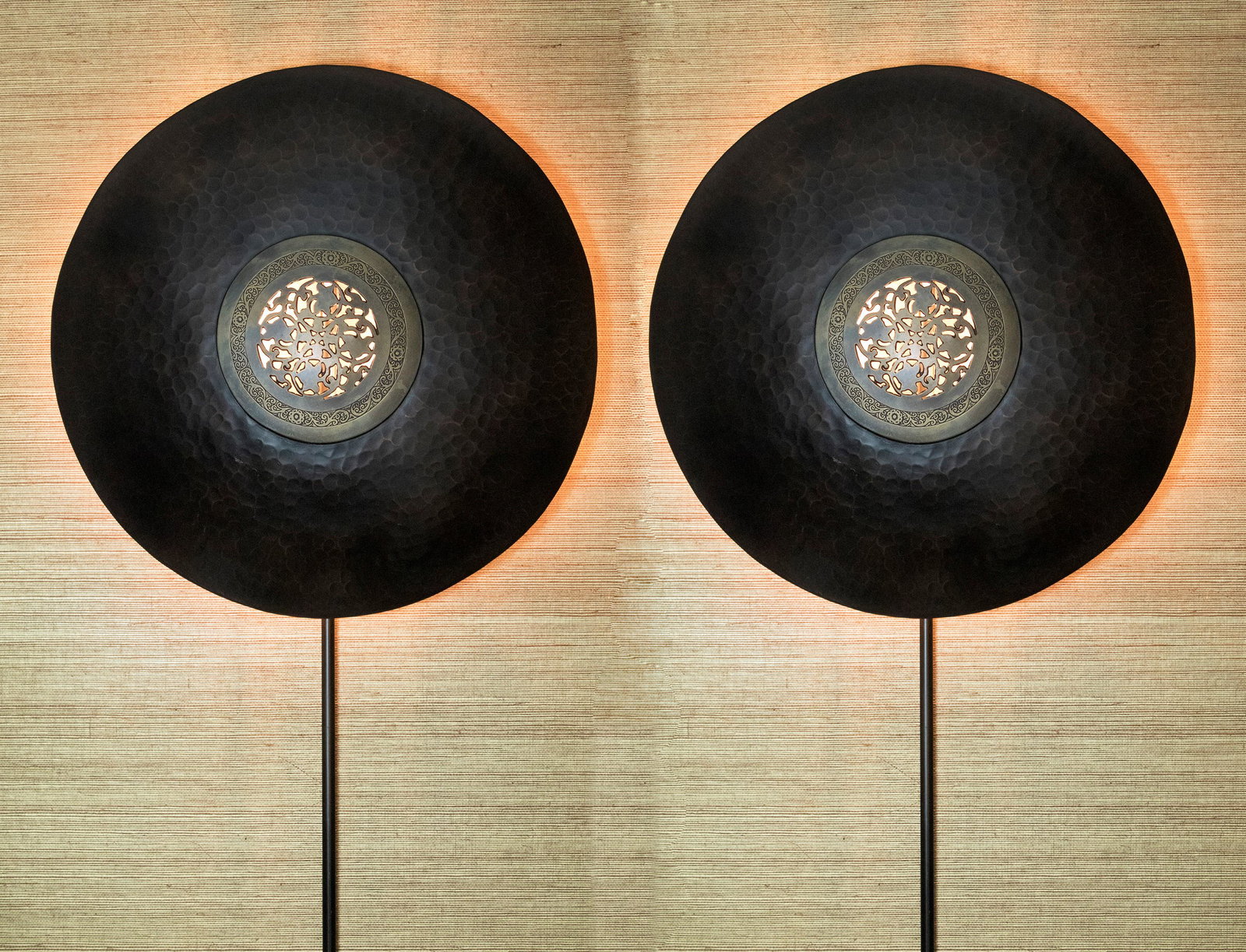 Pr Moroccan Shield Hammered Wall Sconces: DESCRIPTION: Pair of Moroccan hand hammered patinated brass shield shaped wall sconces with filigree decoration to center. MEASUREMENTS: Each 15-1/2" diameter. With conduits 50" high. CONDITION: No de