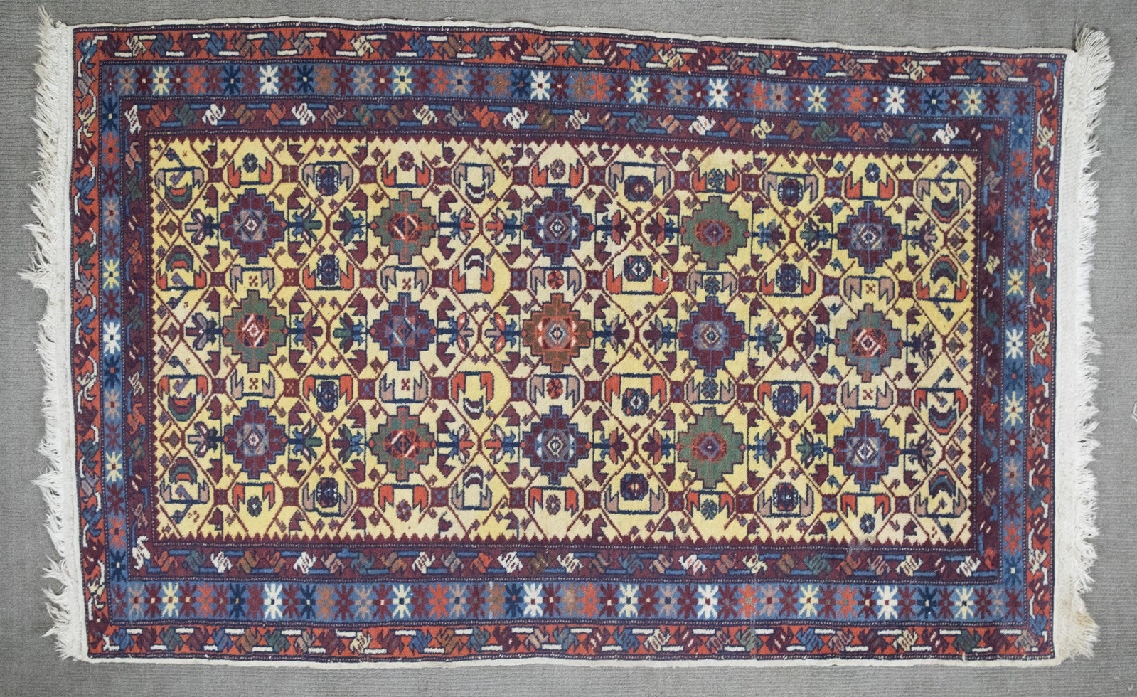 Indian Jaipur Area Rug: DESCRIPTION: Indian Jaipur area rug. 1980's. Green, red, orange, and blue on yellow ground with a blue border. Early 20th Century. MEASUREMENTS: 5'10" x 3'7". CONDITION: Areas of light wear.