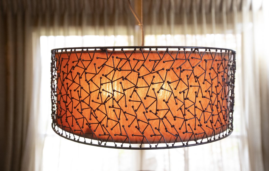 Mid Century Modern Hanging Light: DESCRIPTION: Mid Century Modern hanging light. Drum shade of bronze filigree encircles amber colored fabric. MEASURMENTS: 22" diameter x 9" high. CONDITION: Loss to one section of filigree.
