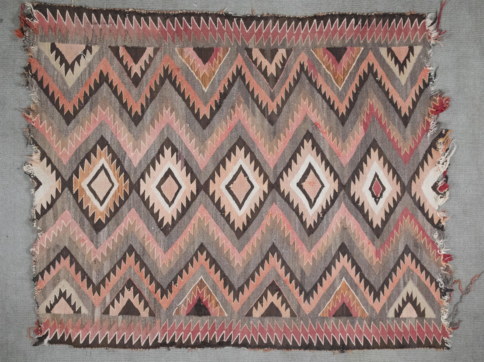 Hand Woven Navajo Eye Dazzler Rug: DESCRIPTION: Hand woven Navajo eye dazzler rug. MEASUREMENTS: 4'8" x 3'11". CONDITION: Areas of wear, fraying to ends.