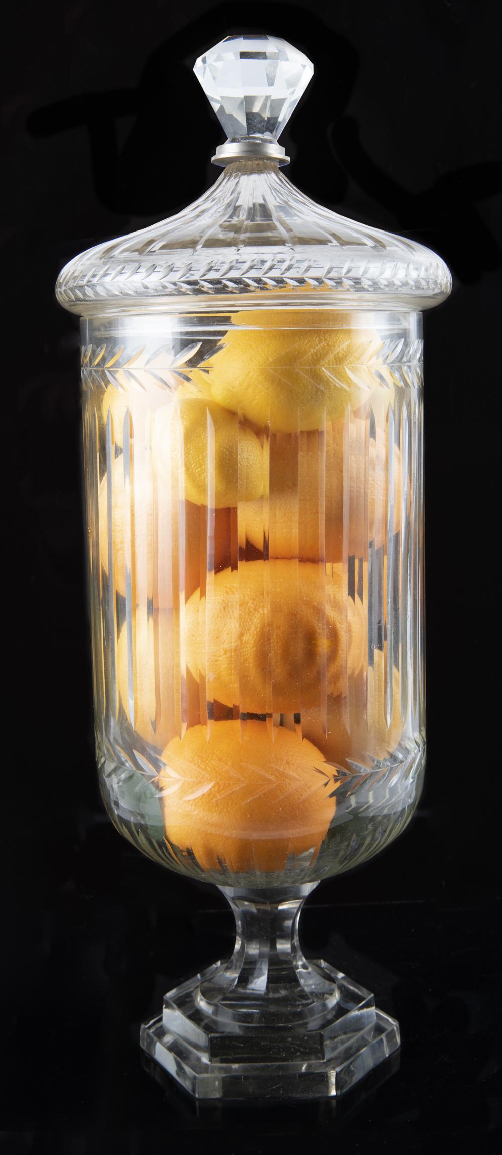 Large Cut Glass Footed Urn with Lid: DESCRIPTION: Large cut glass footed urn with lid. With laurel leaf and line design. MEASUREMENTS: 7" diameter x 19" high. CONDITION: No defects noted.