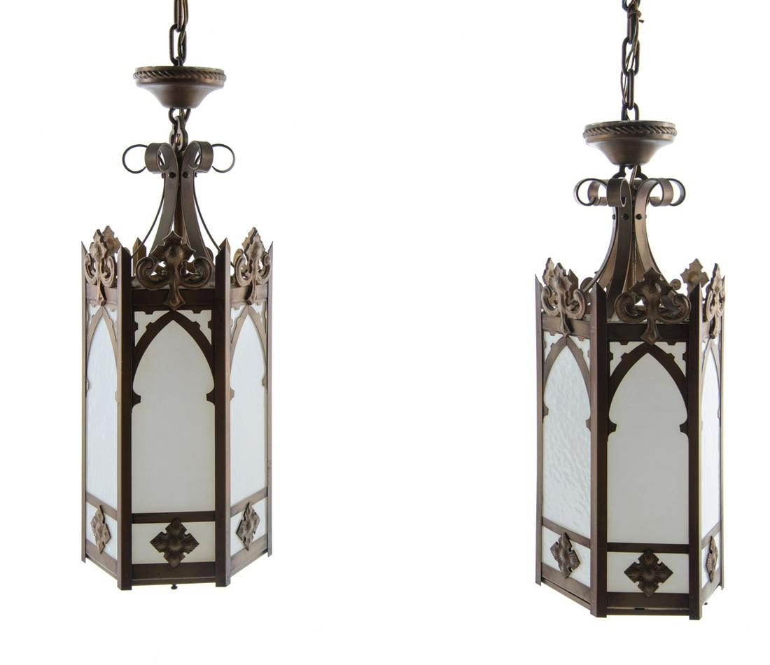 Pair of Hexagonal Gothic Pendant Lights: DESCRIPTION: Pair of hexagonal brass Gothic pendant hanging lights with arches and fleur de lis style details and decorative scrolls. With milk glass panels and bottom lens. MEASUREMENTS: 9-1/2" diame