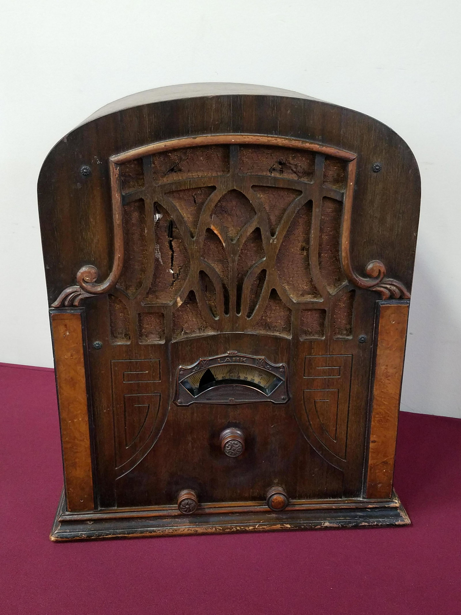 Antique Lark Radio: Powers on but no signal. 15" wide x 9-1/4" deep x 17-3/4" high. Tears to cloth lining. Scratches to wood finish.