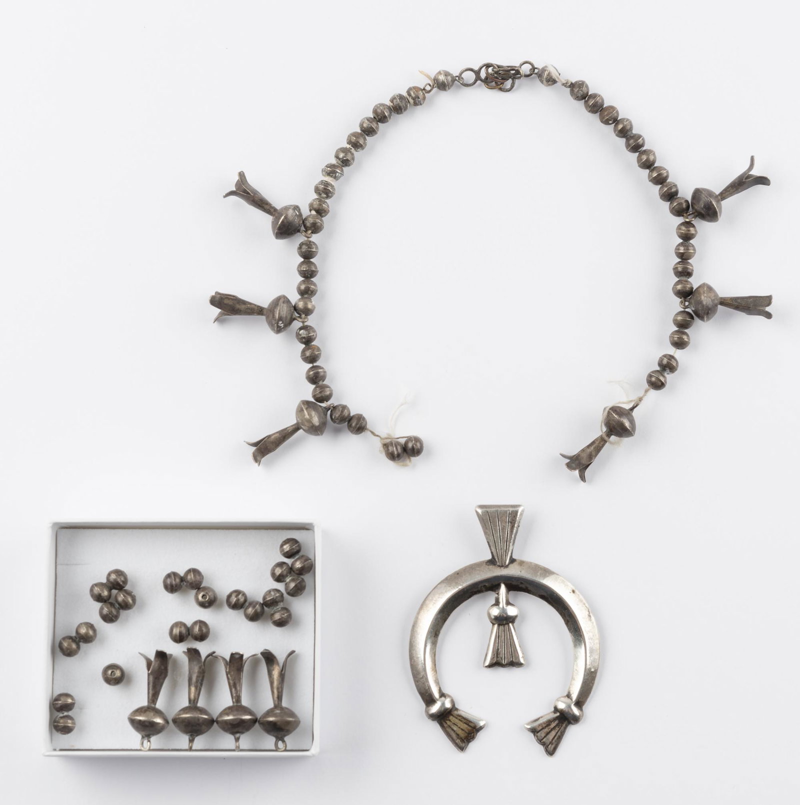 Native American Silver Squash Blossom Necklace: Silver beads and 10 squash blossoms with naja. String is broken. Strung portion 12" long. Naja 2-1/4" wide.