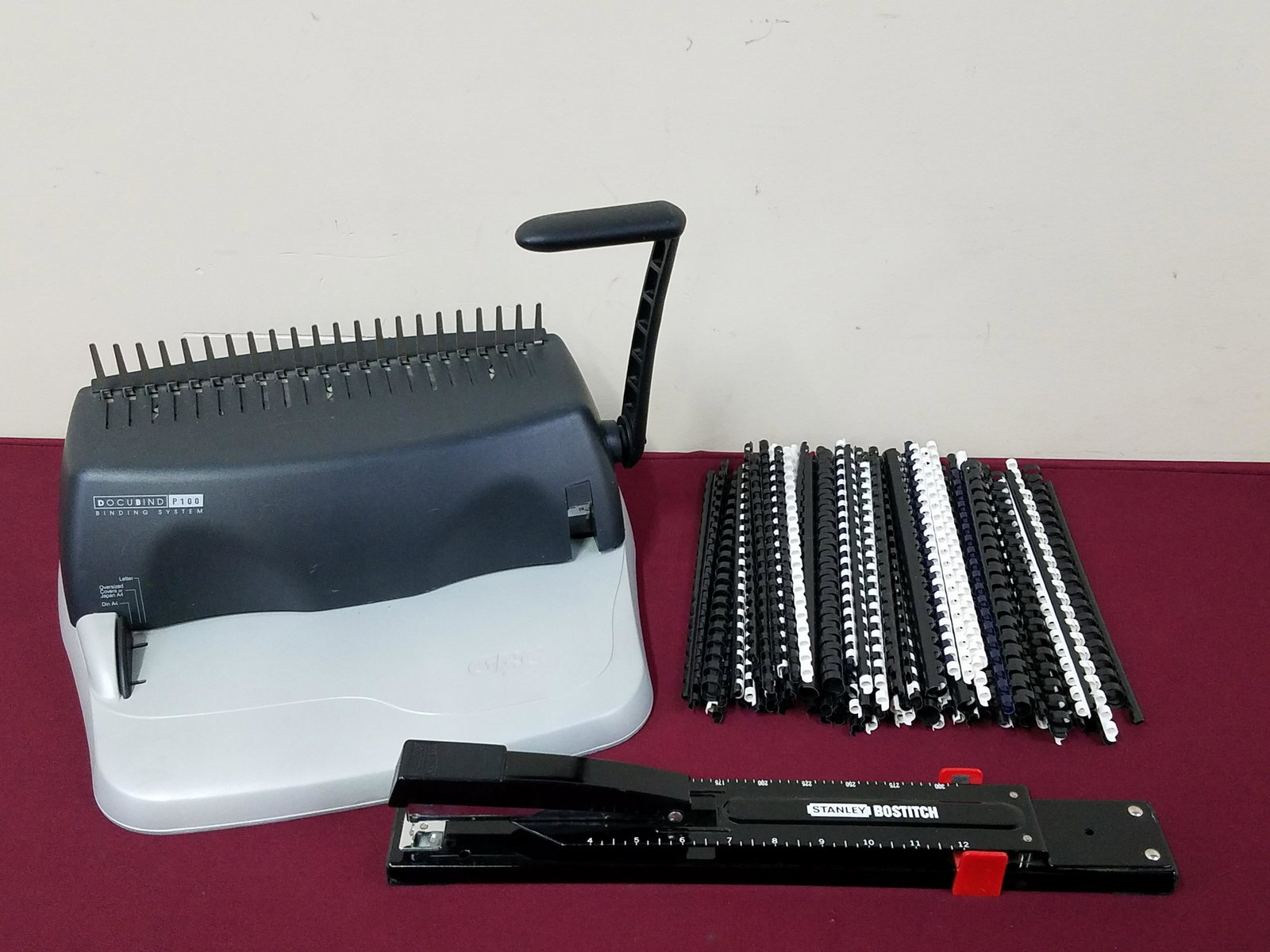 Docubind Binding System and Stanley Stapler: Binder: Model P100. Working. Includes 140 binding rings. 17" wide x 13" high. Stapler: 14" long.