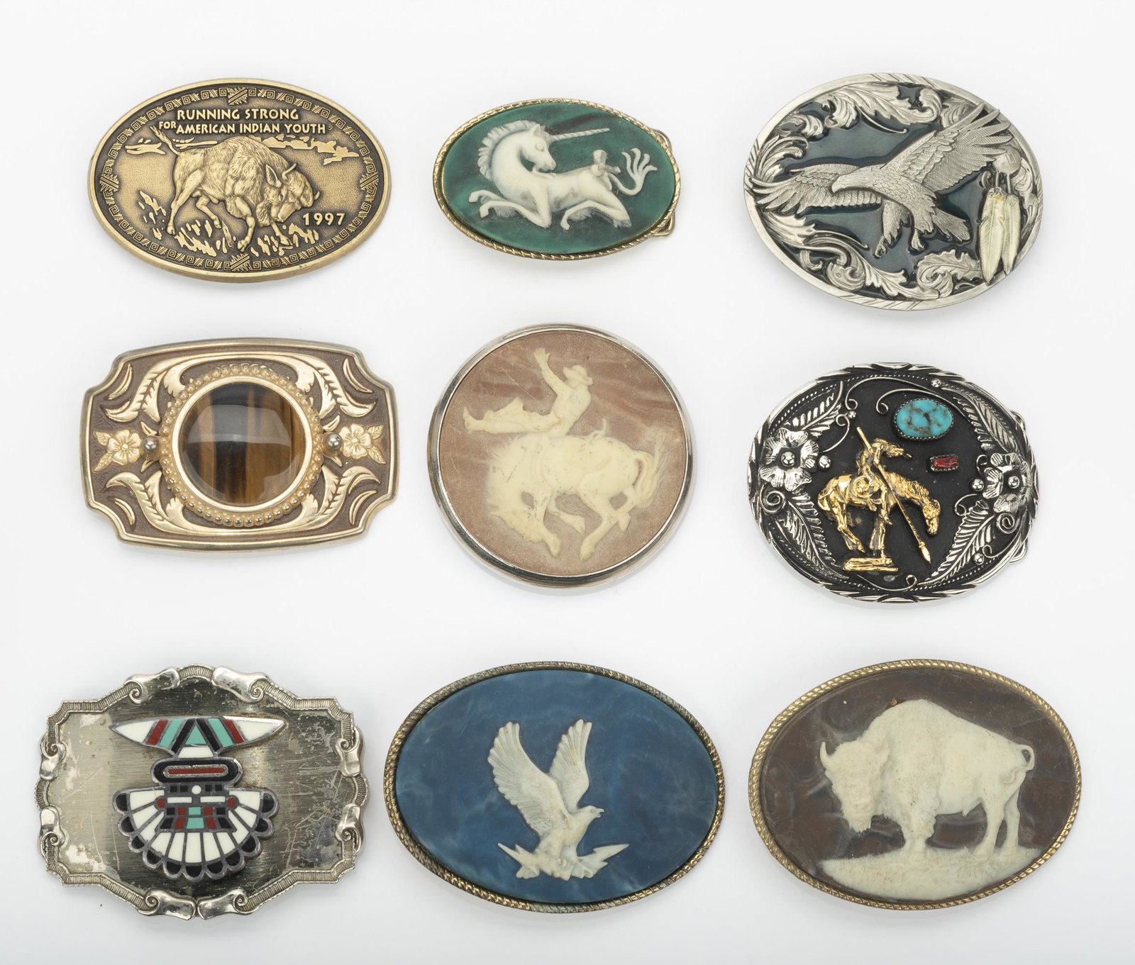 9 Belt Buckles: Includes four with incolay stone - eagle, unicorn, rodeo cowboy, and buffalo; Paintree with turquoise, coral, and onyx; Siskiyou with eagle; buckle with brown gemstone; silver with turquoise and coral