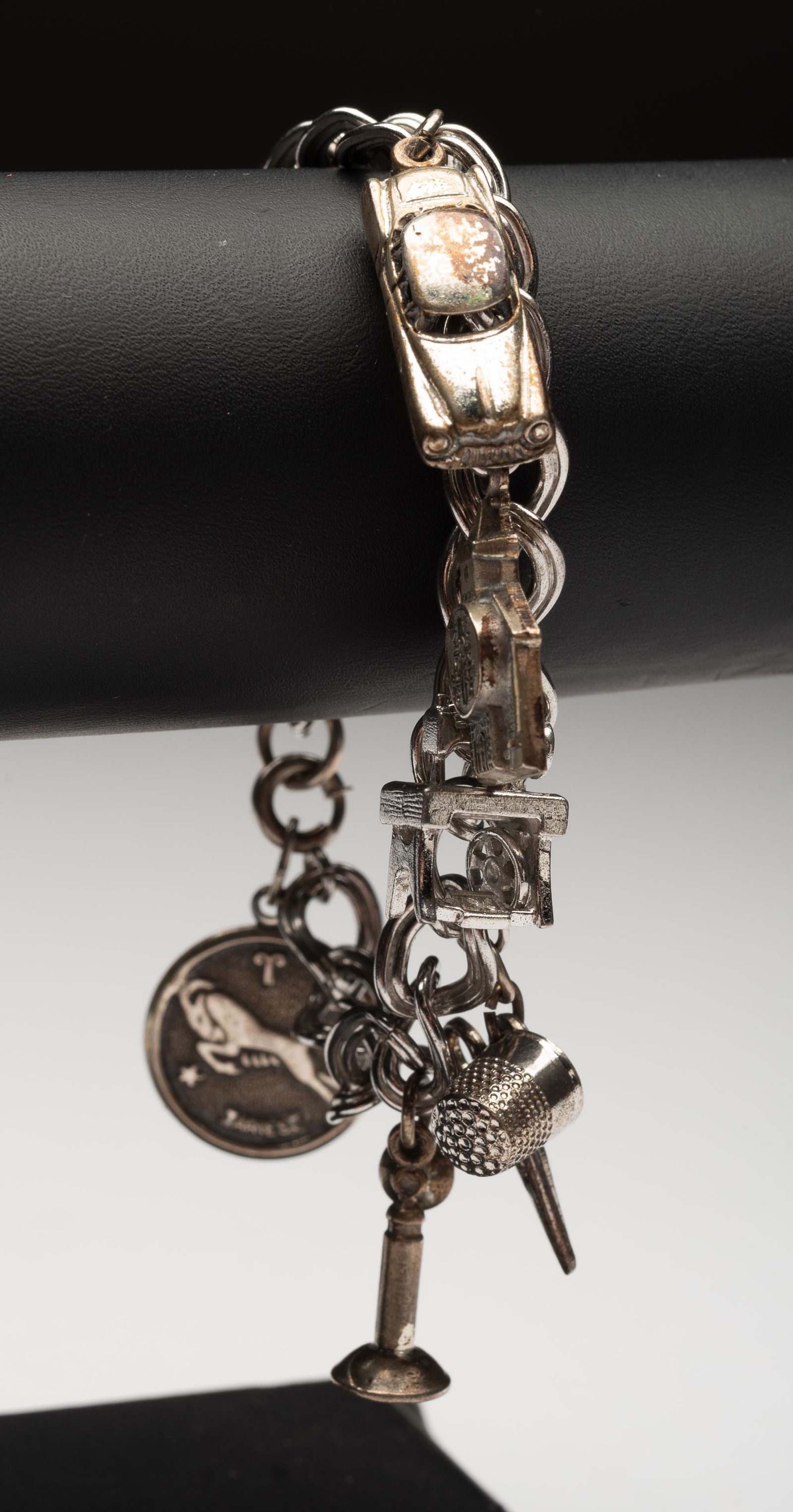 Sterling Charm Bracelet: With nine charms. 7" long. 1.2 ozt. IMPORTANT: Before bidding, please read the terms and conditions below. When you registered for the auction you agreed to these terms and will be required to comply
