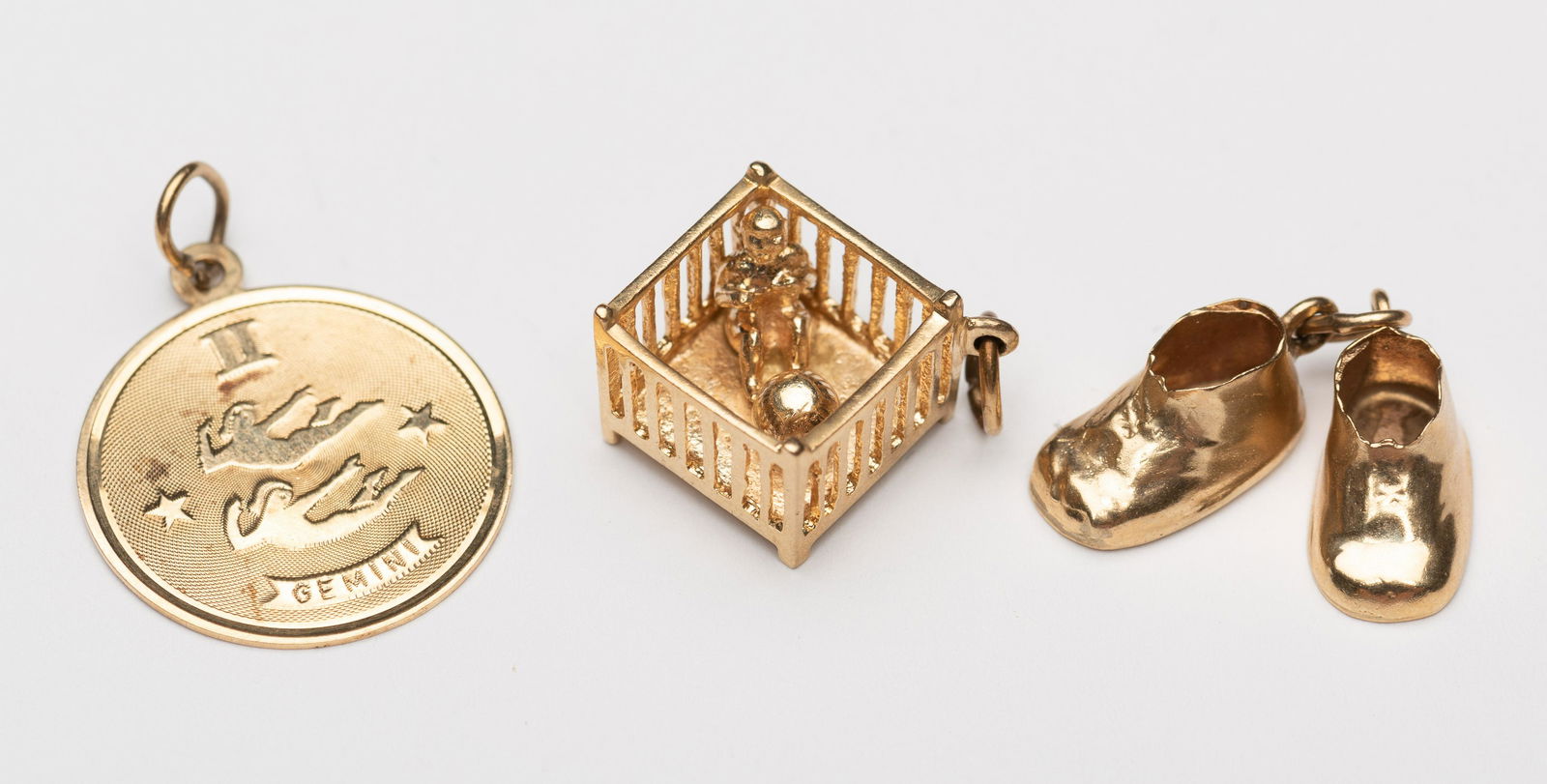 3 14k Charms: Baby shoes, play pen, and Gemini. 1/2" to 15/16". 4.3 dwt. IMPORTANT: Before bidding, please read the terms and conditions below. When you registered for the auction you agreed to these terms and will