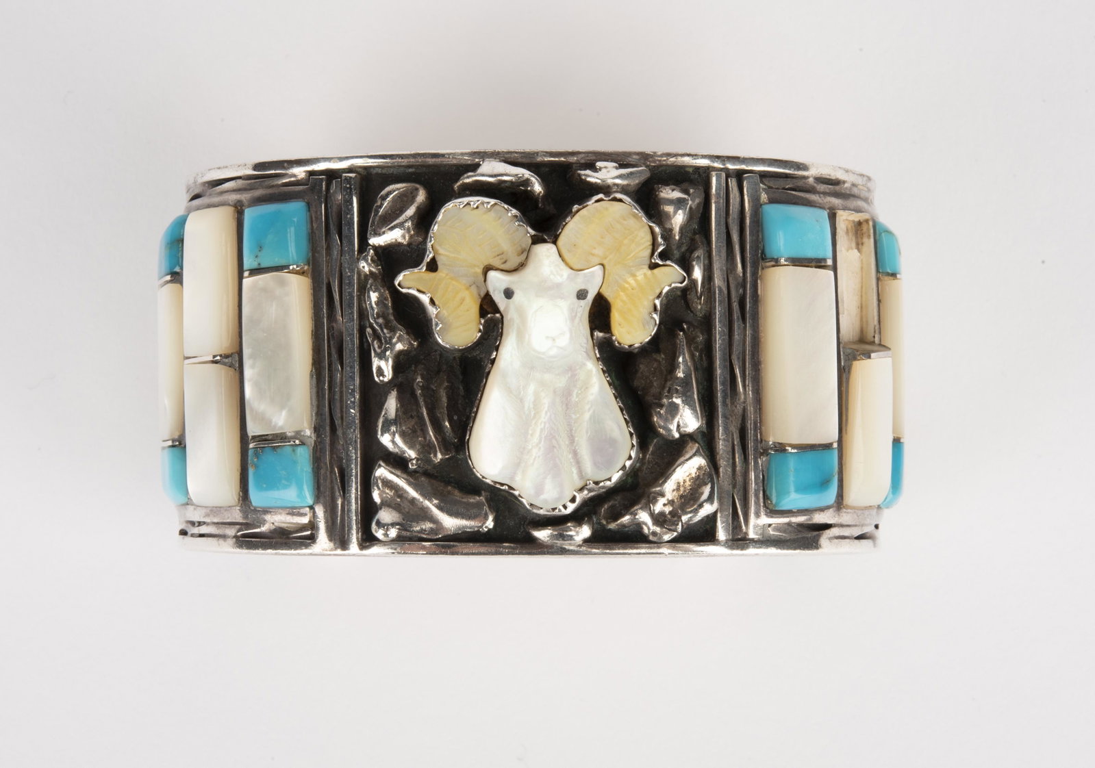 Sterling N. Spencer Cuff Bracelet: DESCRIPTION: Sterling cuff bracelet with mother-of-pearl moose and turquoise. Signed N. Spencer and hallmarked. MEASUREMENTS: Interior 1-3/4" x 2-1/2". 1-1/2" wide. CONDITION: Light wear. Missing one 