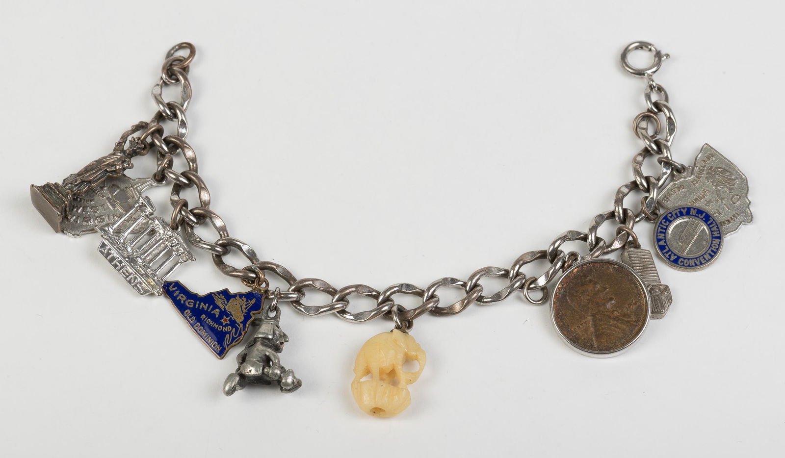 Sterling Charm Bracelet: Silver, sterling, penny, and bone charms. 7" long. IMPORTANT: Before bidding, please read the terms and conditions below. When you registered for the auction you agreed to these terms and will be requ