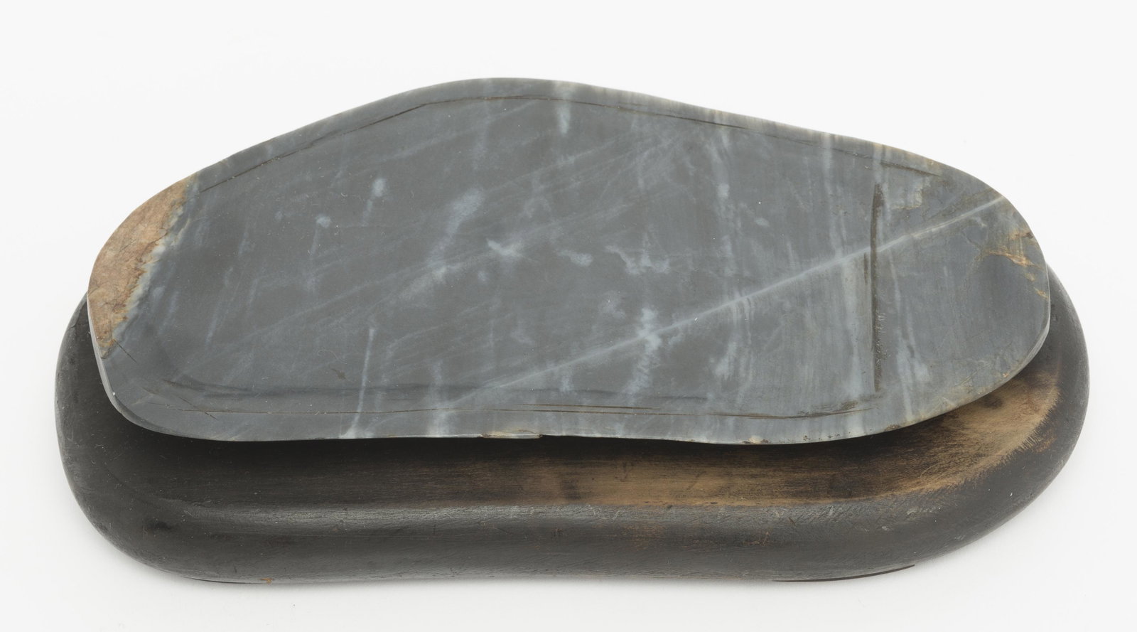 Chinese Duan Inkstone: Chinese Duan calligraphy inkstone, on formed wood base. MEASUREMENTS: 9" long x 3-1/2" deep x 2" high. CONDITION: No defects noted.