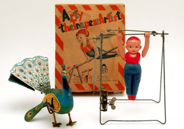 Wind-Up Toys Peacock & Arty the Trapeze Artist: DESCRIPTION: Lot of two wind-up toys. One 7" x 5-1/2" lithographed tin peacock, unmarked. Together with a 10-1/4" (extended) celluloid and metal Arty the Trapeze Artist by Toyland Toys (Made in Occupi