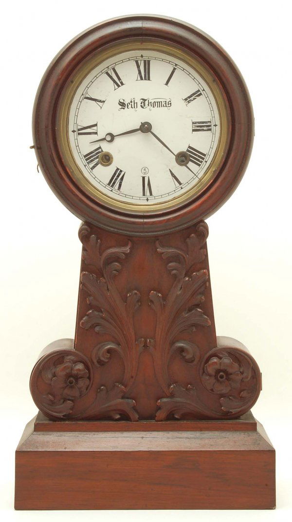Seth Thomas Mantle Clock: DESCRIPTION: A Seth Thomas mantle clock having a carved mahogany case, painted porcelain dial marked "Seth Thomas" and brass works marked with Seth Thomas logo and "Made in U.S. America 8-1/4". Time a