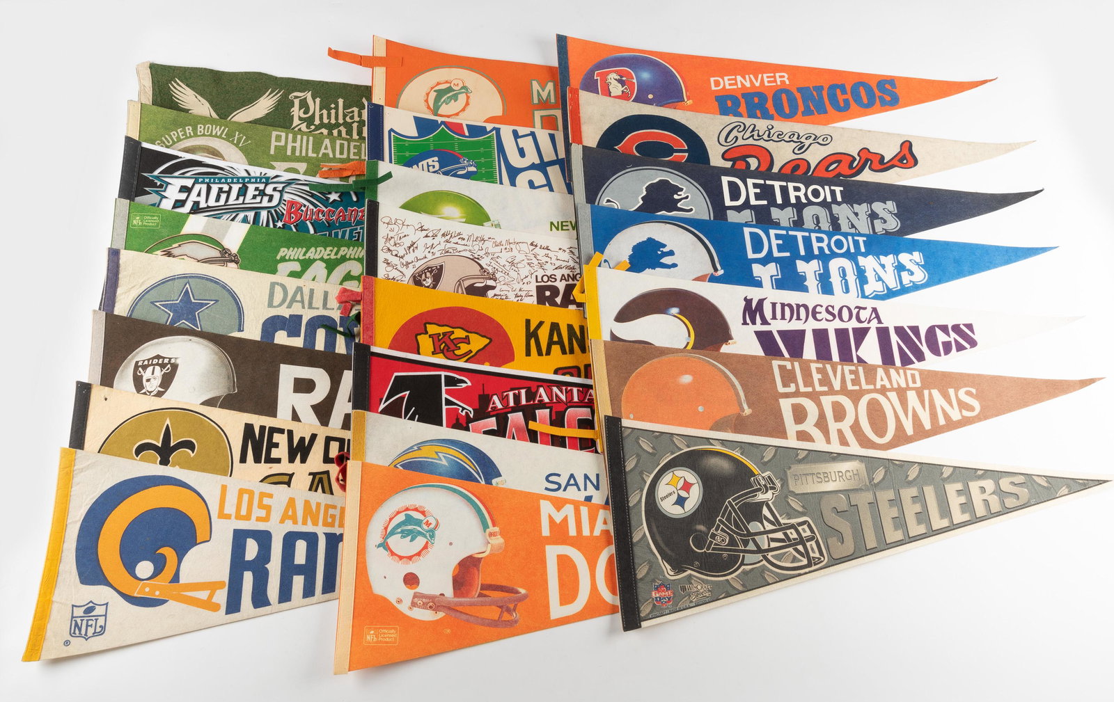 23 N. F. L Football Pennants 1950's-1980's: DESCRIPTION: Includes Eagles, Cowboys, Raiders, Saints, Rams, Steelers, and more. CONDITION: Some wear. IMPORTANT: Before bidding, please read the terms and conditions. When you registered for the auc