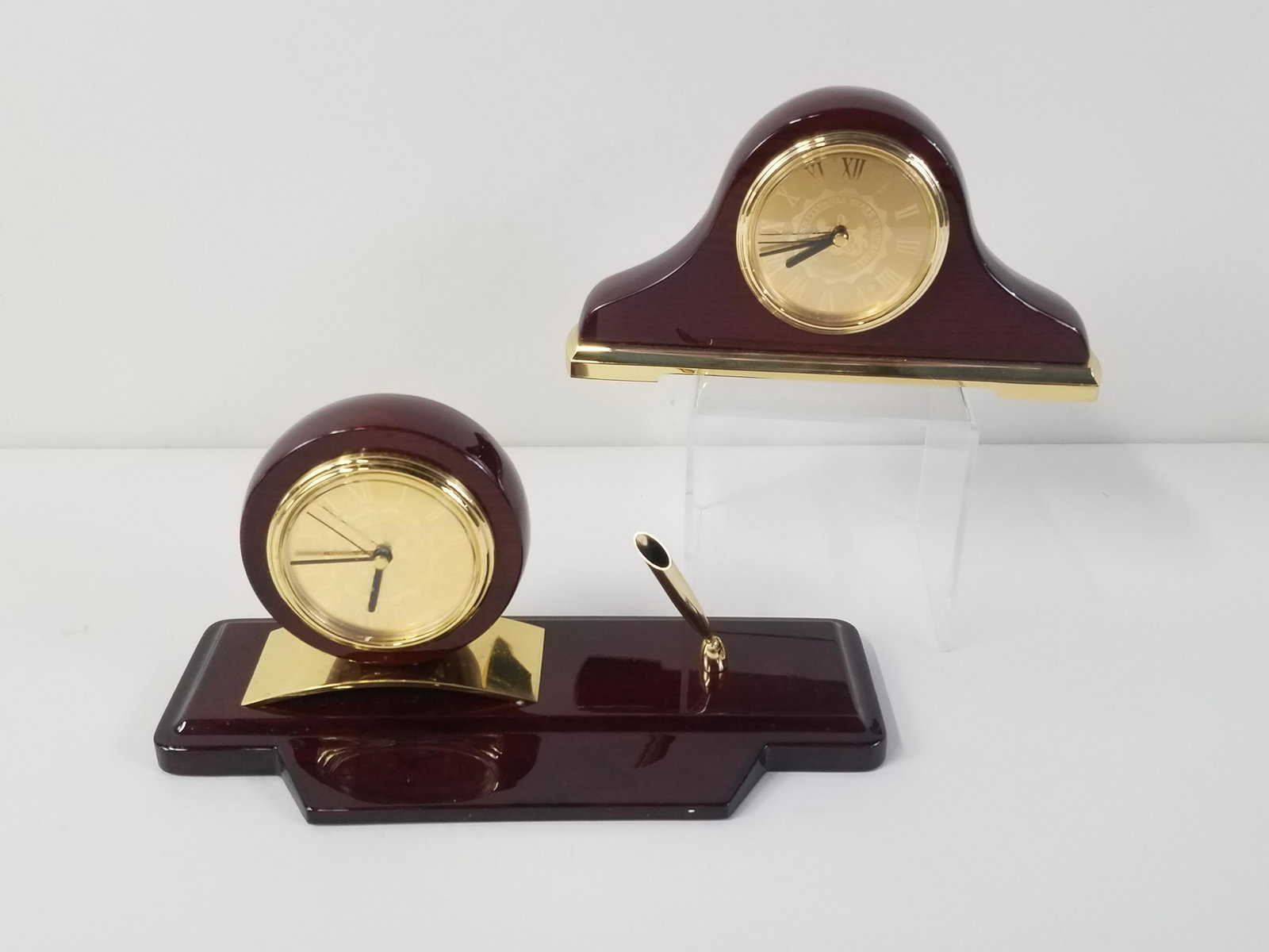 2 Pennsylvania State University Desk Clocks: One with pen holder. Battery operated. 4-1/4" to 4-3/4" high. IMPORTANT: Before bidding, please read the terms and conditions. When you registered for the auction you agreed to these terms and will be