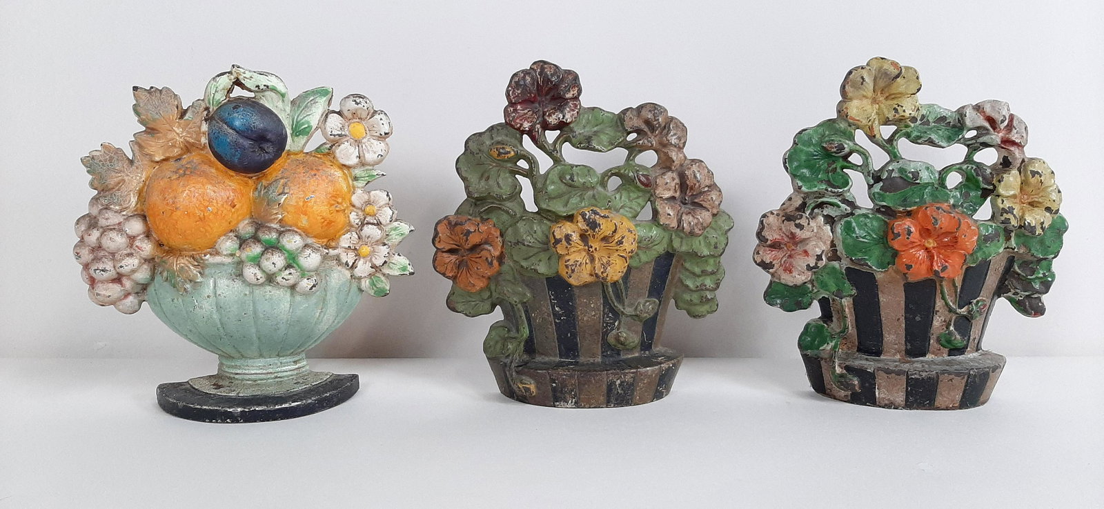 3 Floral Cast Iron Doorstops: 6½" to 6¾" wide X 1½" to 1¾" deep X 7" to 7¼" high. IMPORTANT: Before bidding, please read the terms and conditions. When you registered for the auction you agreed to these terms and will be requ