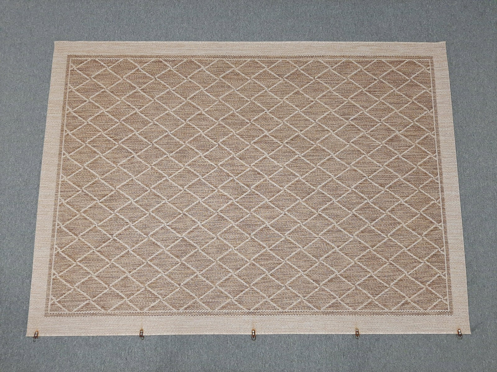 Woven Indoor/Outdoor Area Rug: With 5 metal loop hangers along one side. Some rust spots around hangers. 5'3" wide X 7'4" long. IMPORTANT: Before bidding, please read the terms and conditions. When you registered for the auction yo