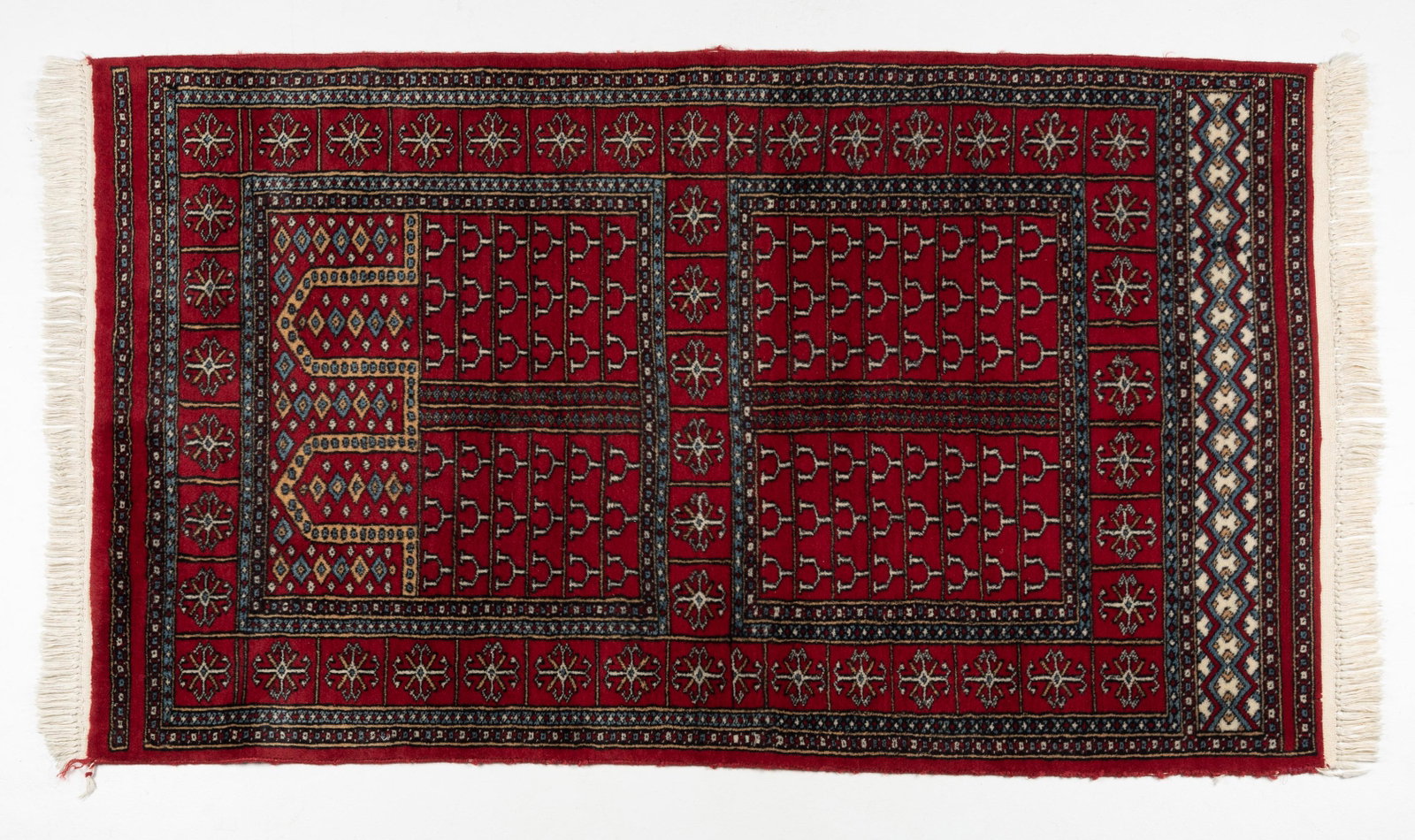 Pakistan Prayer Rug: DESCRIPTION: Pakistan prayer rug. Red ground with blue and cream highlights. Last quarter of the 20th century. MEASUREMENTS: 5 ' 5 " long x 3 ' 1-1/2 " wide. CONDITION: Wear to binding and fringe. IMP