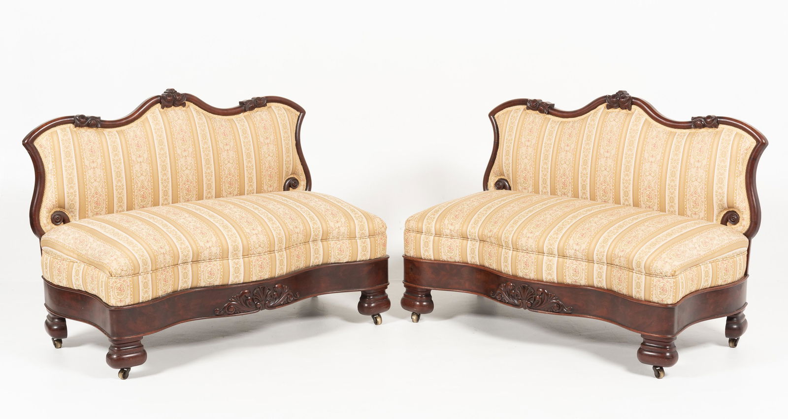 Pair of Victorian Settees: DESCRIPTION: Pair of Victorian settees. Mahogany wood frame with carved details and turned feet on casters. Upholstered and stuffed. MEASUREMENTS: 45 " long x 22 " wide x 33 " high. IMPORTANT: Before