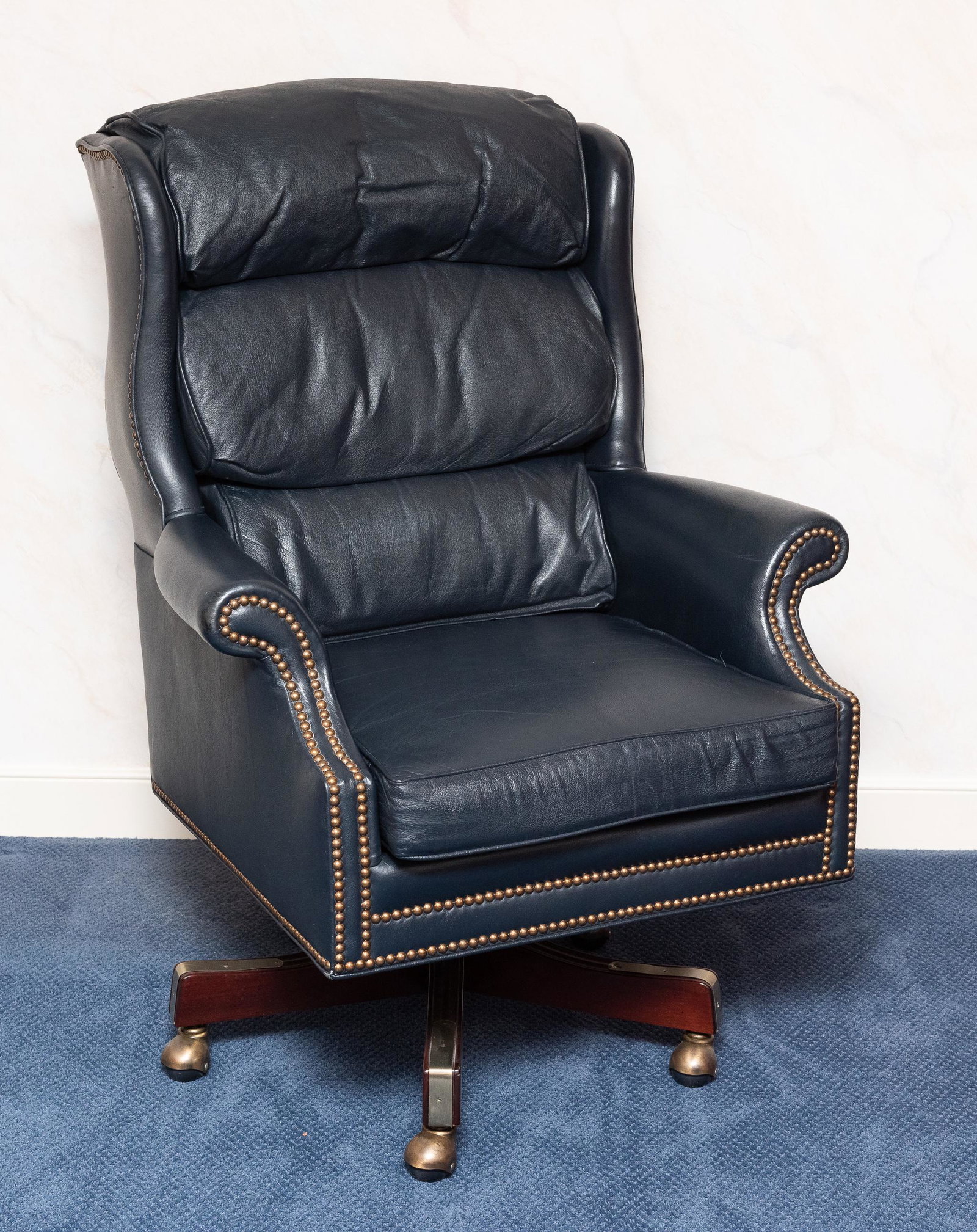 Classic Leather, Inc. Executive Chair: Top grain navy blue leather. Nail head trim to arms, brushed brass casters. 32" wide x 29" deep x 44" high. IMPORTANT: Before bidding, please read the terms and conditions. When you registered for the
