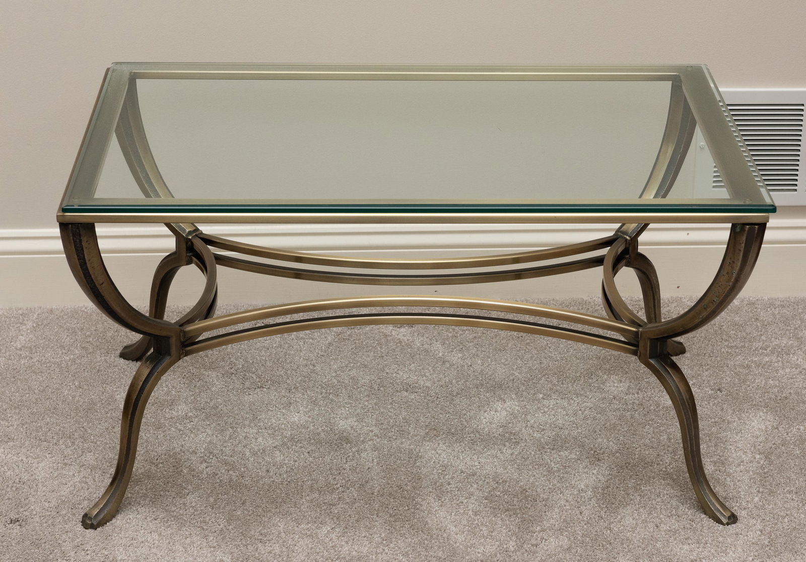 Glass Top Coffee Table: Steel base with brushed bronze finish. 34" wide x 22" deep x 18" high. IMPORTANT: Before bidding, please read the terms and conditions. When you registered for the auction you agreed to these terms an