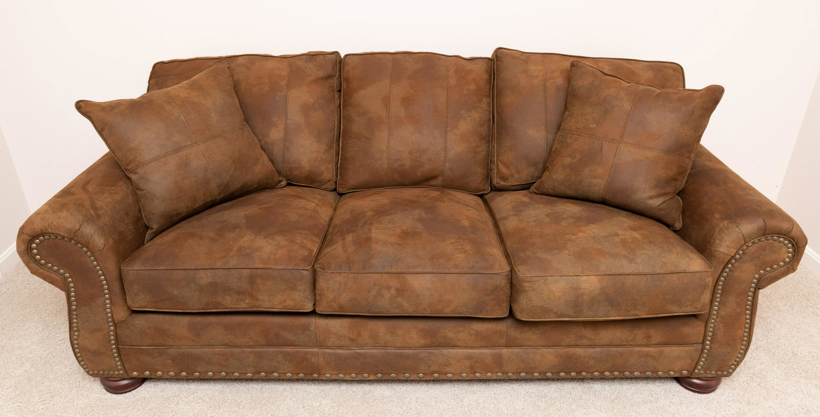 Brown Microfiber Sofa: With nail head trim and two throw pillows. 87" wide x 38" deep x 36" high. IMPORTANT: Before bidding, please read the terms and conditions. When you registered for the auction you agreed to these term