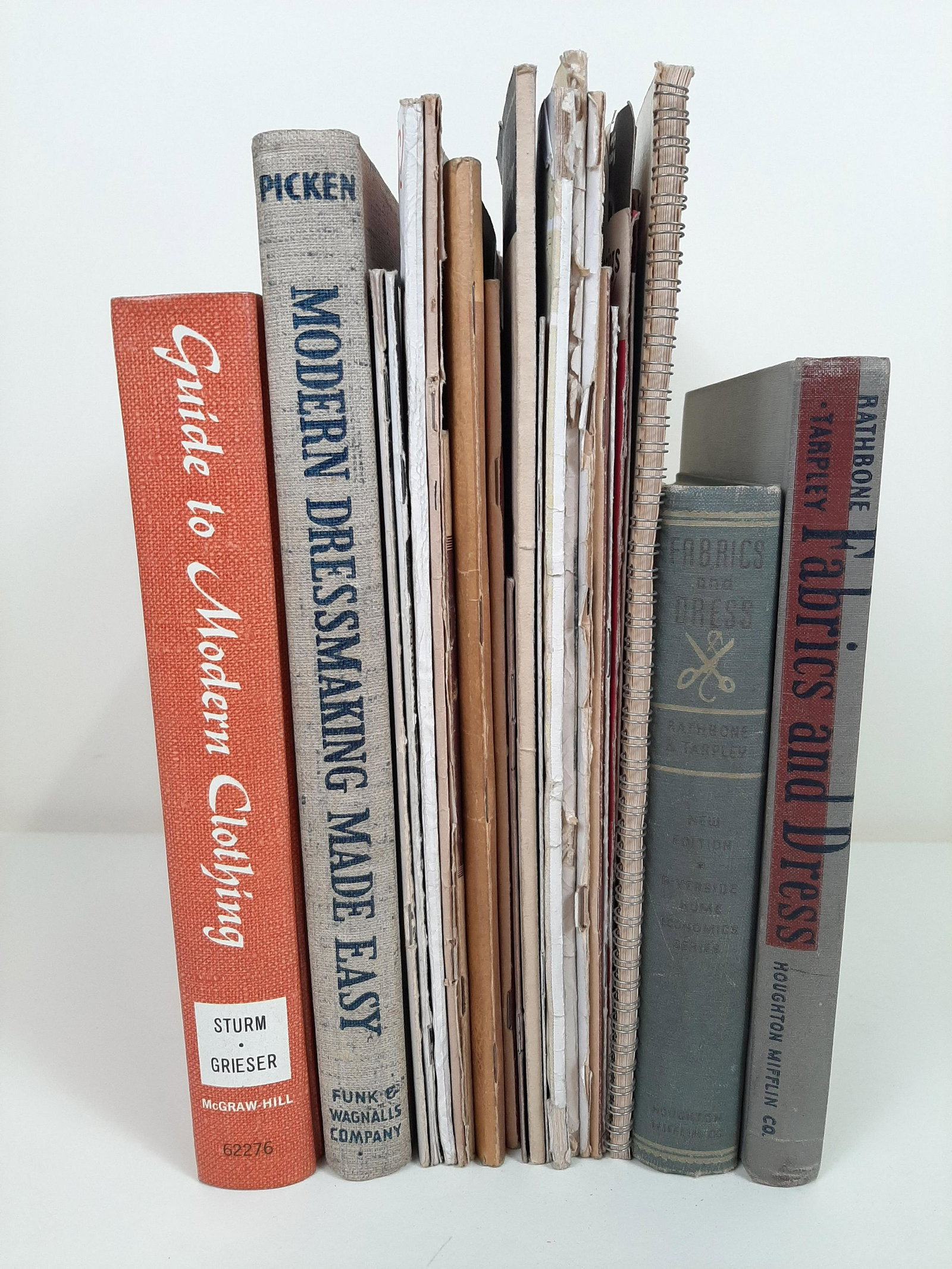 22 Books and Pamphlets on Dressmaking and Fabrics: Includes Fabrics and Dress by Lucy Rathbone and Elizabeth Tarpley, copyright 1937 and 1943, Modern Dressmaking Made Easy by Mary Brooks Picken copyright 1940, Singer guides and manuals, Vogue's Book o