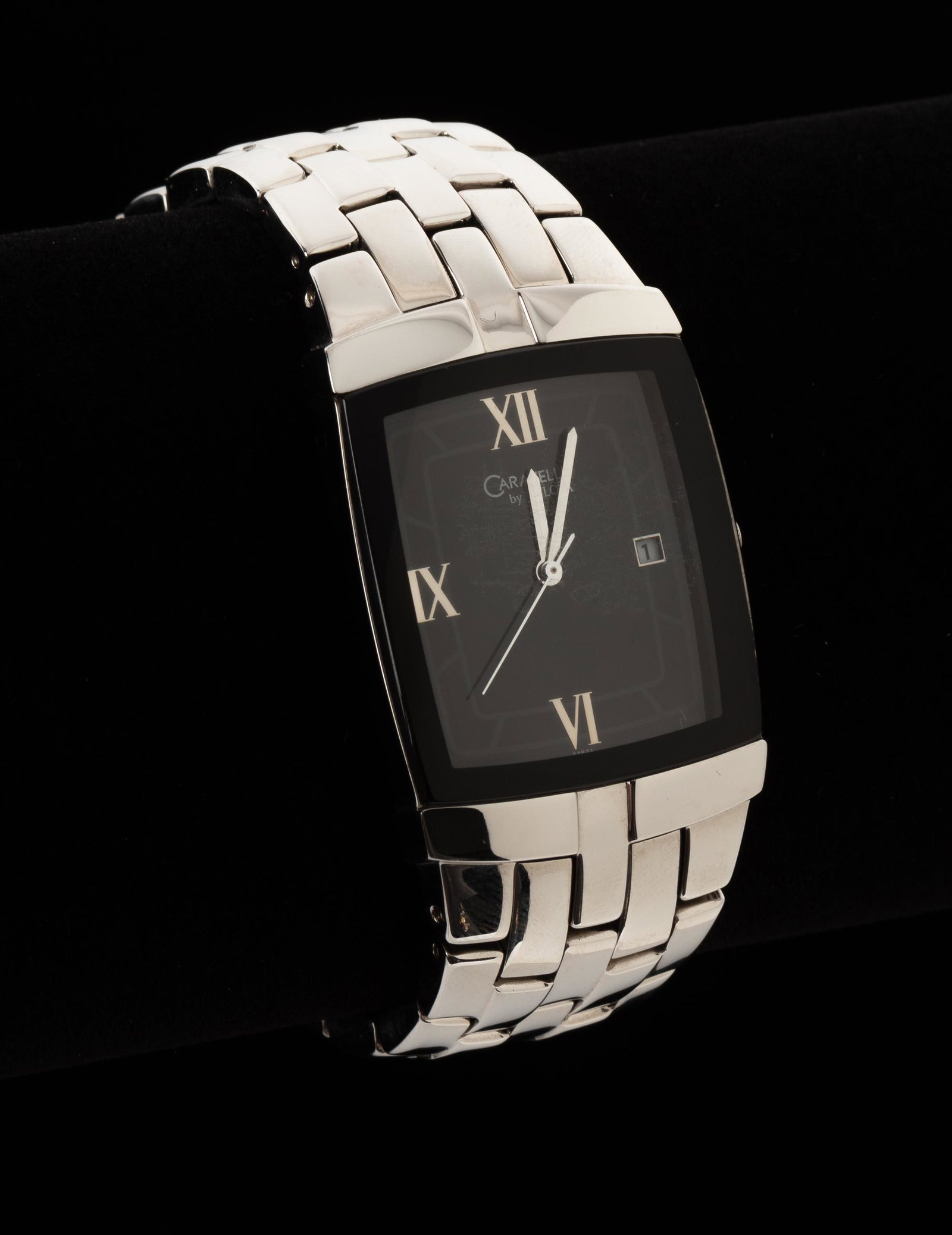 Bulova Caravelle Wristwatch: Rectangular black face with roman numerals and inset date. Quartz movement. 1-3/4" lug to lug; 1-1/8" wide on adjustable stainless steel bracelet. Running. IMPORTANT: Before bidding, please read the t