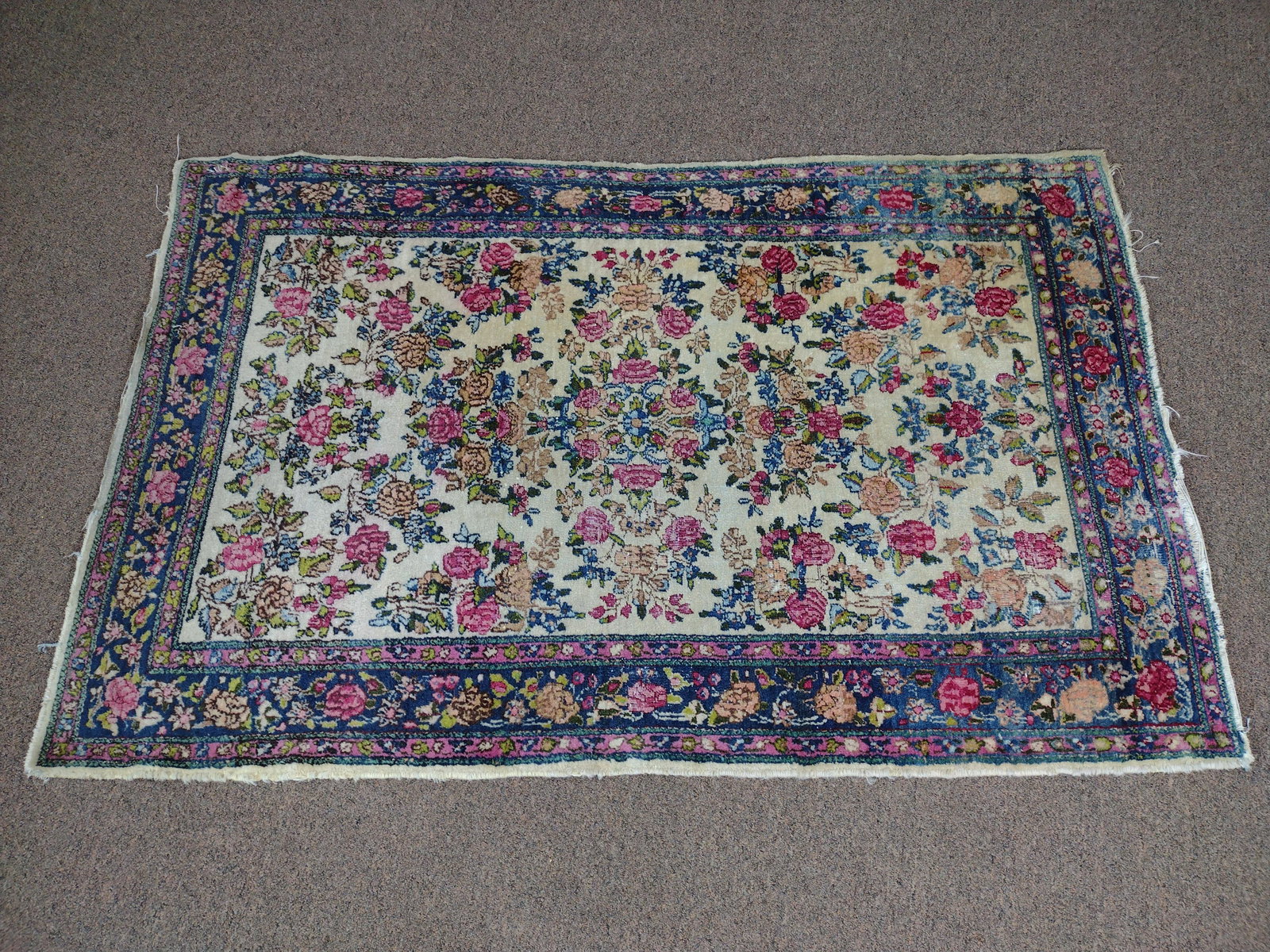 Hand Knotted Wool Area Rug: Allover floral design in red, blue and tan on beige ground. First half of 20th century. 36" wide x 59" long. Some fading. Losses to fringe and wear to carpet. IMPORTANT: Before bidding, please read th
