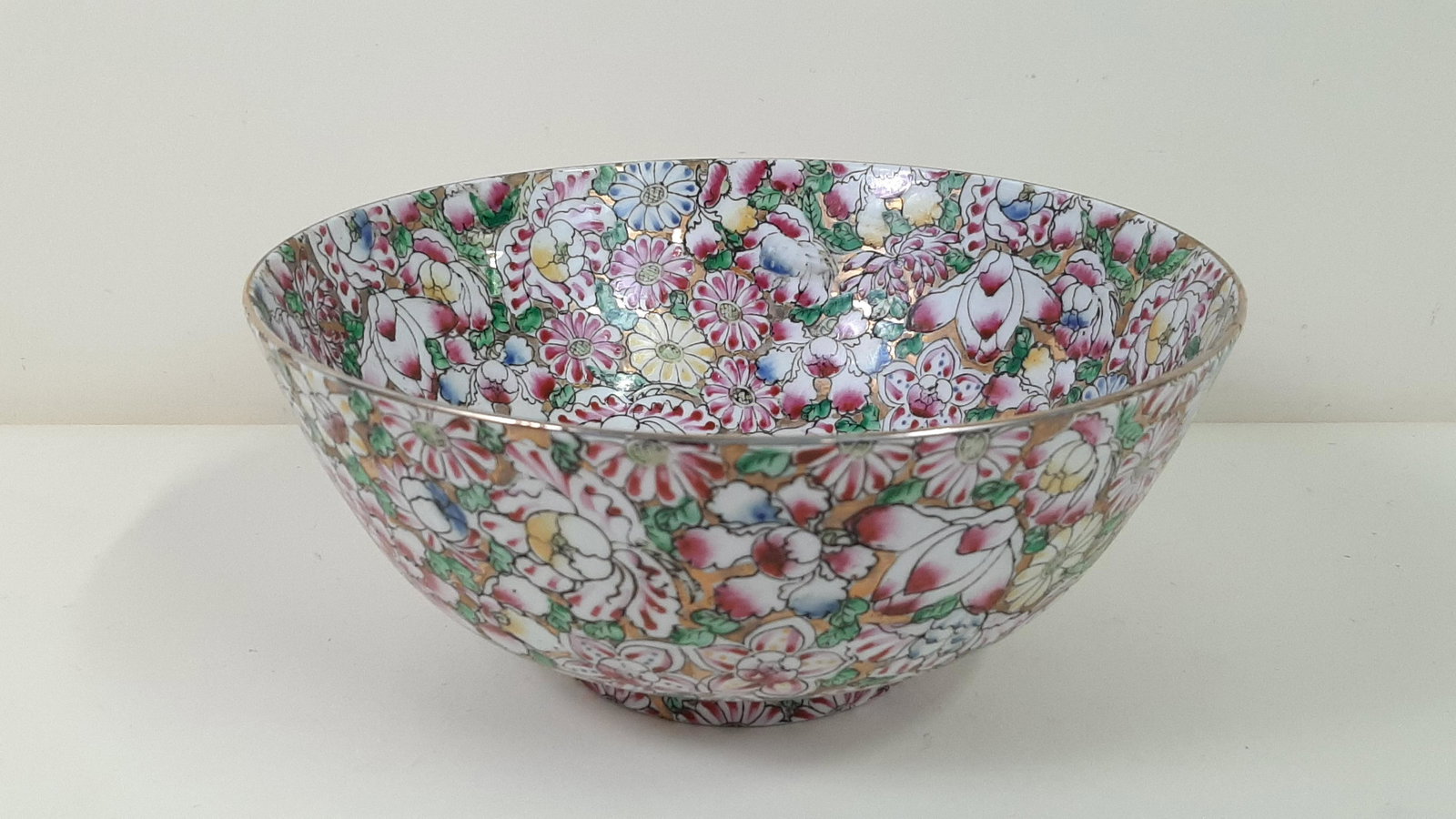 Famille Rose Gold Ground Mille Fleurs Bowl: 4 Character Qianlong mark. 10-1/4" diameter X 4-1/2" high. IMPORTANT: Before bidding, please read the terms and conditions. When you registered for the auction you agreed to these terms and will be re