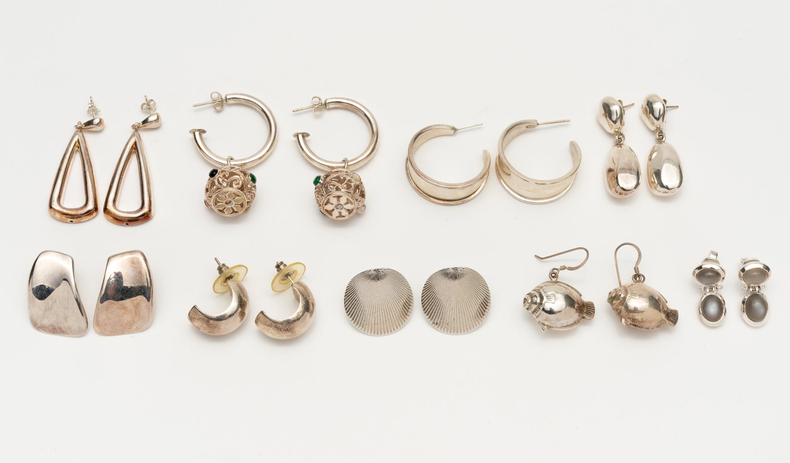 9 Pairs of Sterling and Silver Earrings: All pierced. Includes tapered hoops signed ATI Mexico. 1" to 2" long. IMPORTANT: Before bidding, please read the terms and conditions. When you registered for the auction you agreed to these terms and
