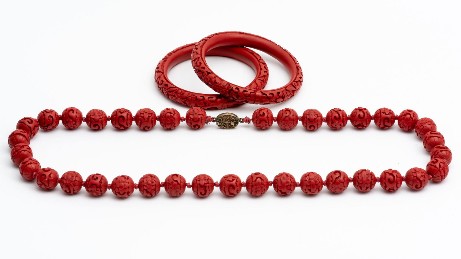 3 Pieces Cinnabar Jewelry: Necklace 24" long. Bangles 2 -1/2" diameter. IMPORTANT: Before bidding, please read the terms and conditions. When you registered for the auction you agreed to these terms and will be required to comp