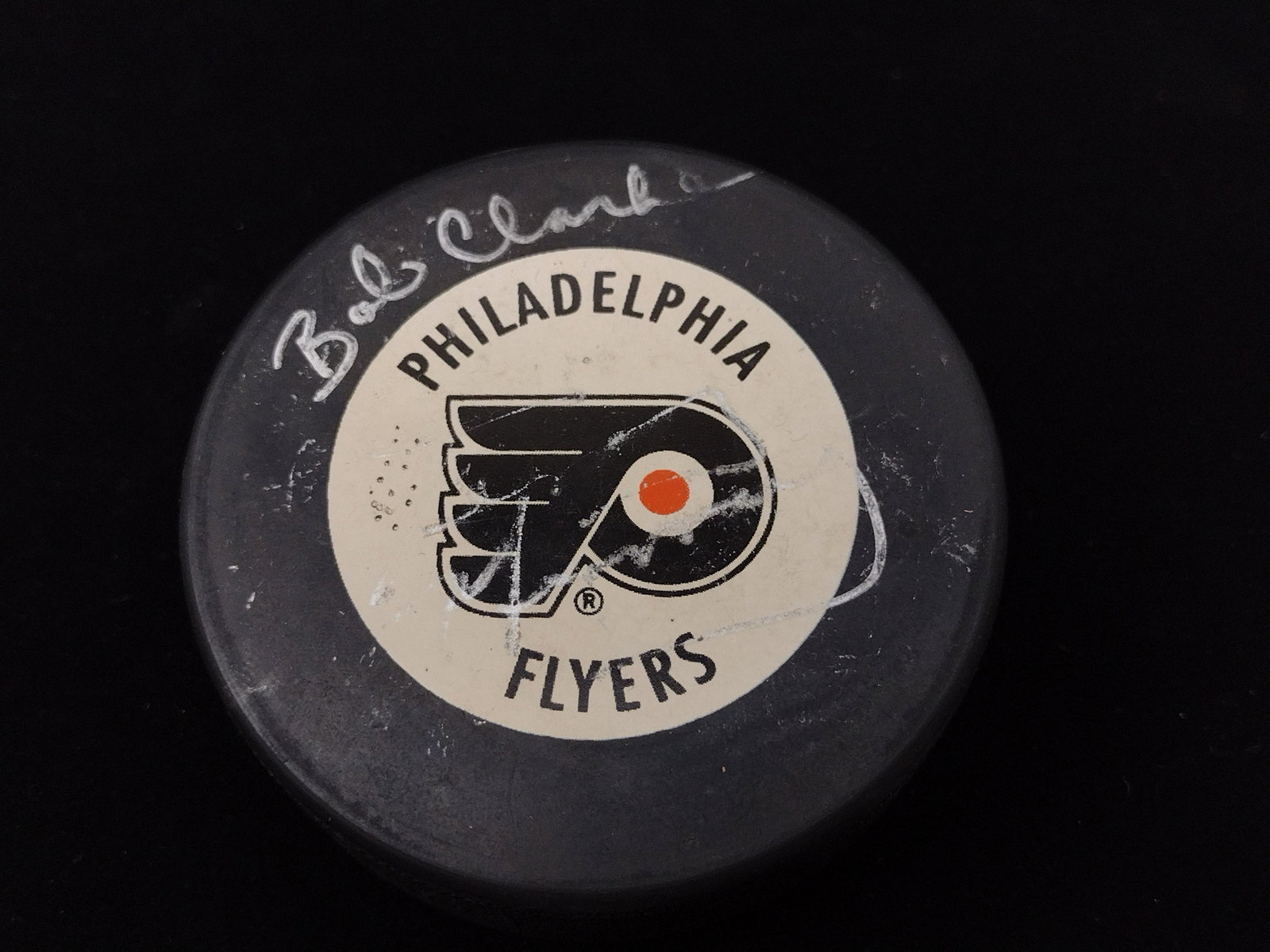 Bob Clarke Autographed Hockey Puck: In case. 3-1/2" high x 3" wide. DP. IMPORTANT: Before bidding, please read the terms and conditions. When you registered for the auction you agreed to these terms and will be required to comply with t