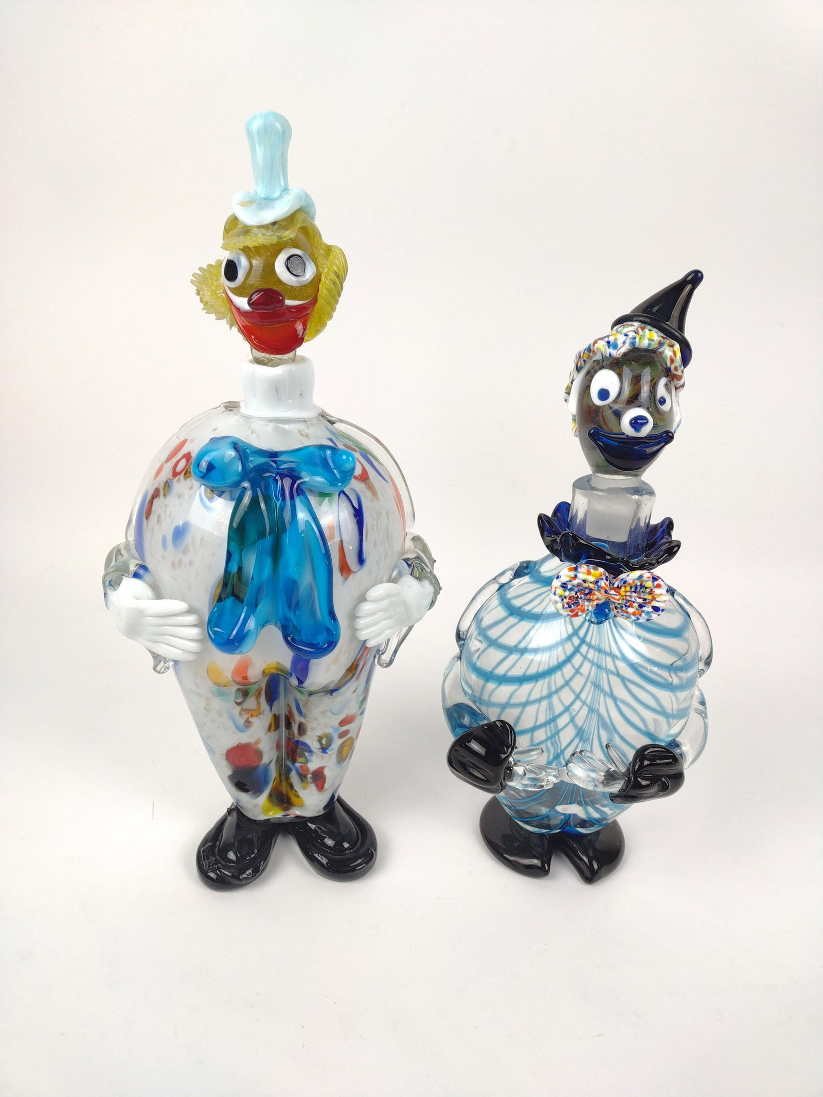2 Art Glass Clown Decanters: One marked with red foil crown sticker. Other unmarked. 13" to 15" high. JK IMPORTANT: Before bidding, please read the terms and conditions. When you registered for the auction you agreed to these ter
