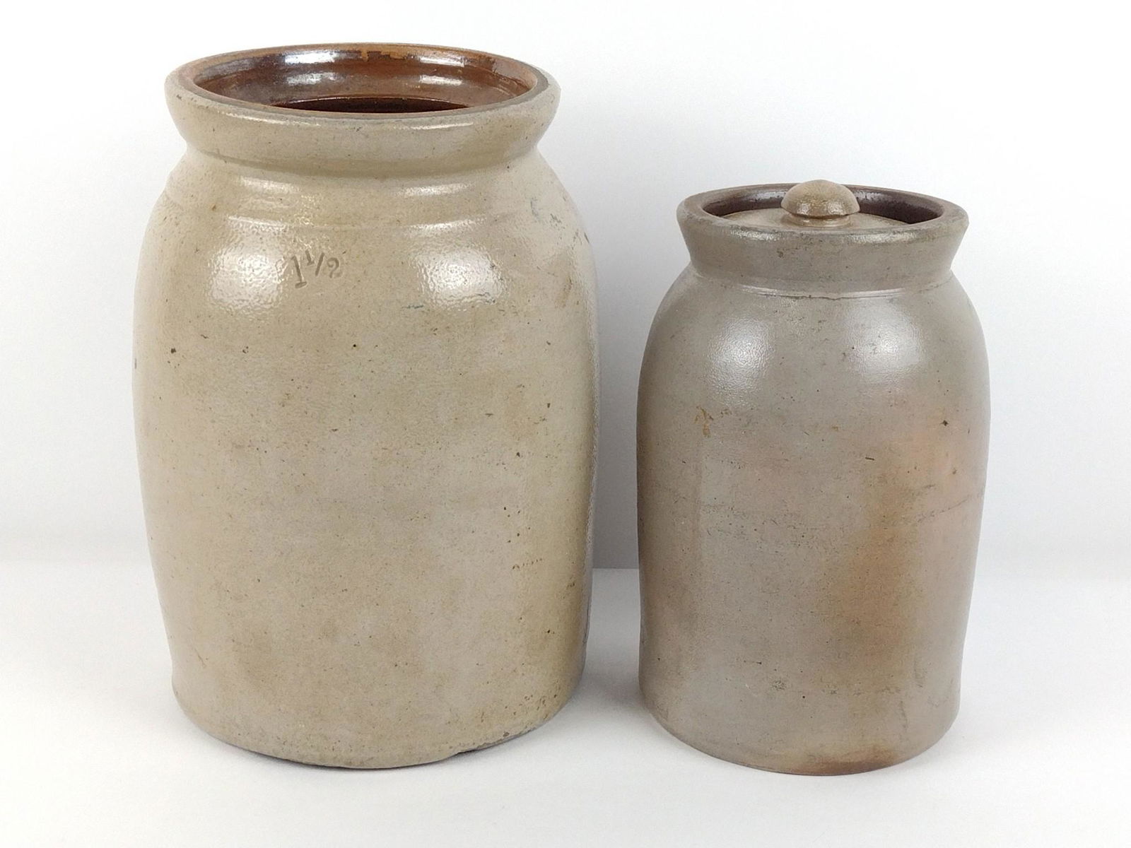 2 Stoneware Jars: Both unmarked. 8-1/2" to 10-1/4" high x 5-1/4" to 7-1/4" base diameter. Chips and losses to both. Cracks to larger. DP. IMPORTANT: Before bidding, please read the terms and conditions. When you regist