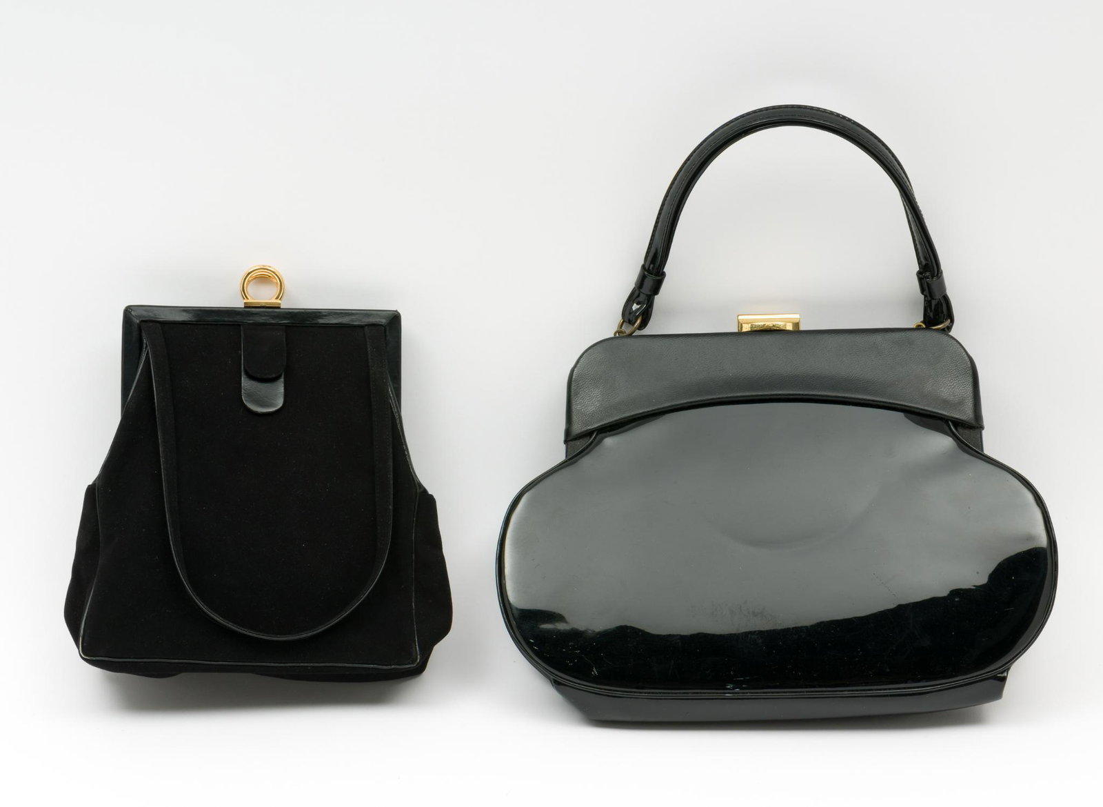 2 Mid-Century Black Evening Bags: Includes Koret noncrockable suede "Koretolope" handbag and Lewis patent leather handbag. Both clutch strap with clasp enclosure and interior pockets. Lewis handbag includes original comb and Koret inc