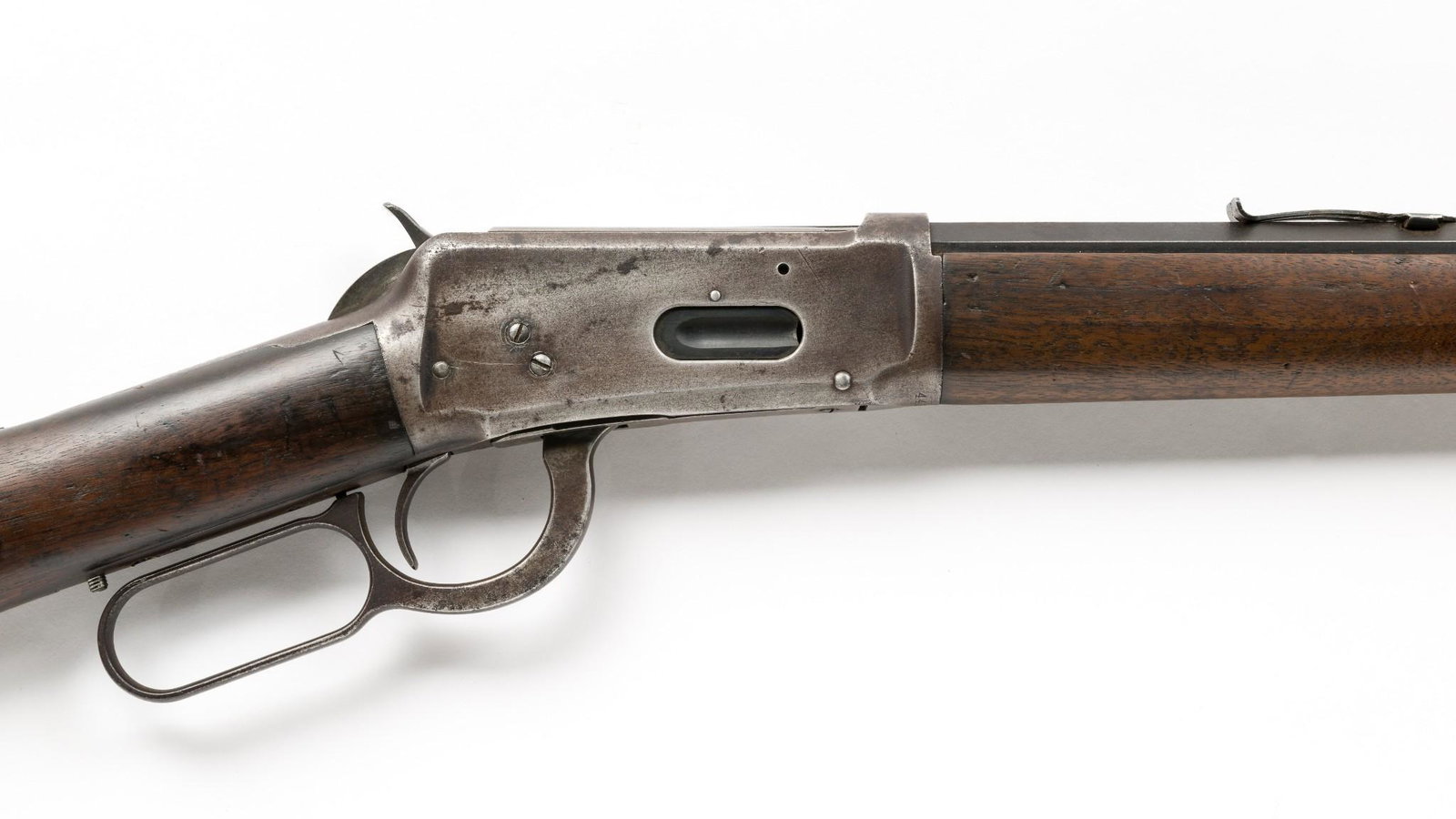 Early Winchester Model 1894 Carbine, Caliber .30 WCF: Serial Number: 445307 Design: Winchester manufactured in 1908. 17-1/2" octagonal barrel, chambered for the .30 WCF cartridge. Steel butt plate. Leaf rear sight with repair. Drilled and tapped for a pe