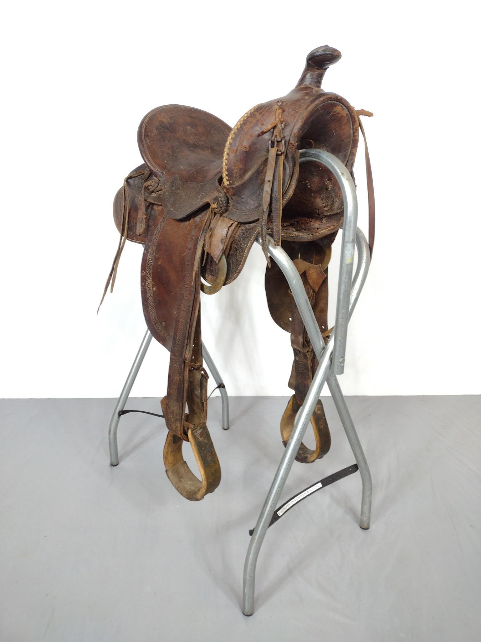 Tooled Leather Western Saddle With Stirrups: 22-1/2" wide X 57" deep X 35" high. Has some discoloring. Saddle stand not included. MG. IMPORTANT: Before bidding, please read the terms and conditions. When you registered for the auction you agreed