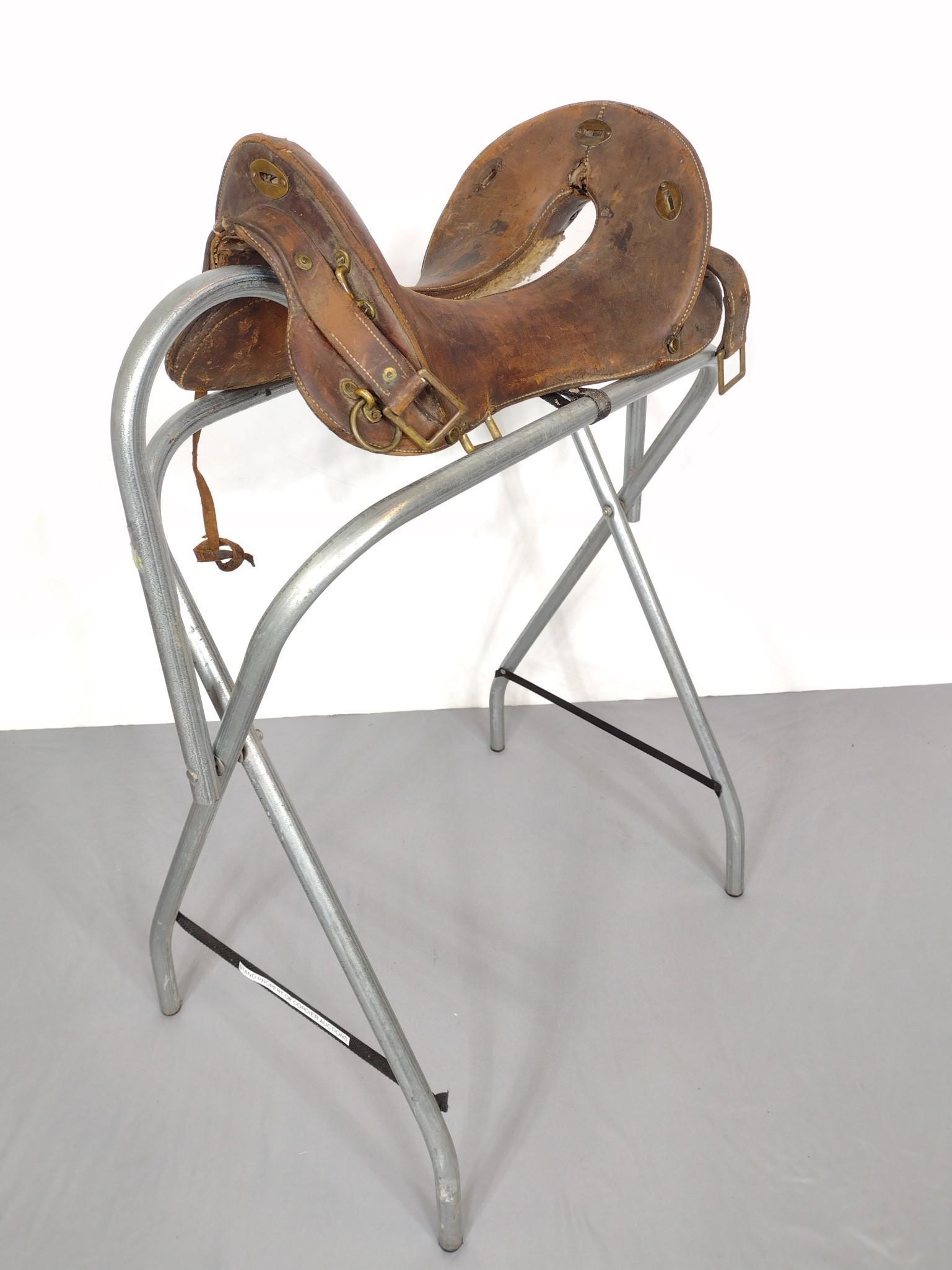 Antique Brown Western Saddle With Brass Fittings: 13" wide X 19" deep X 10" high. Has some scratches and discoloring. Saddle stand not included. MG. IMPORTANT: Before bidding, please read the terms and conditions. When you registered for the auction 